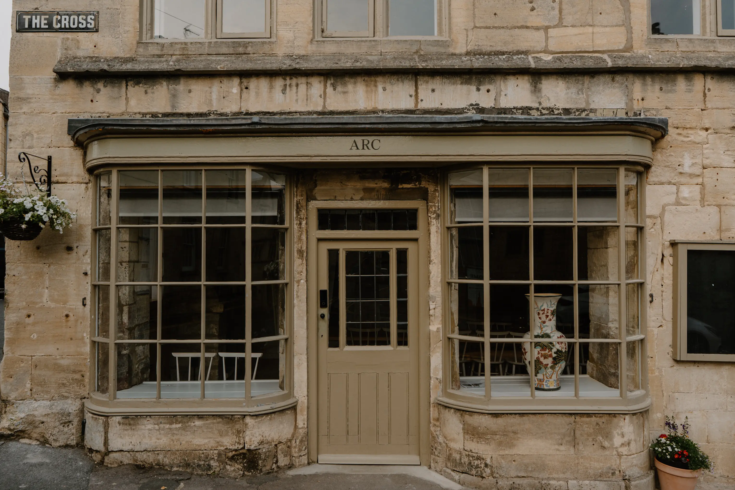 The Cotswold stone shopfront and entrance of ARC Painswick with ARC signage in the window