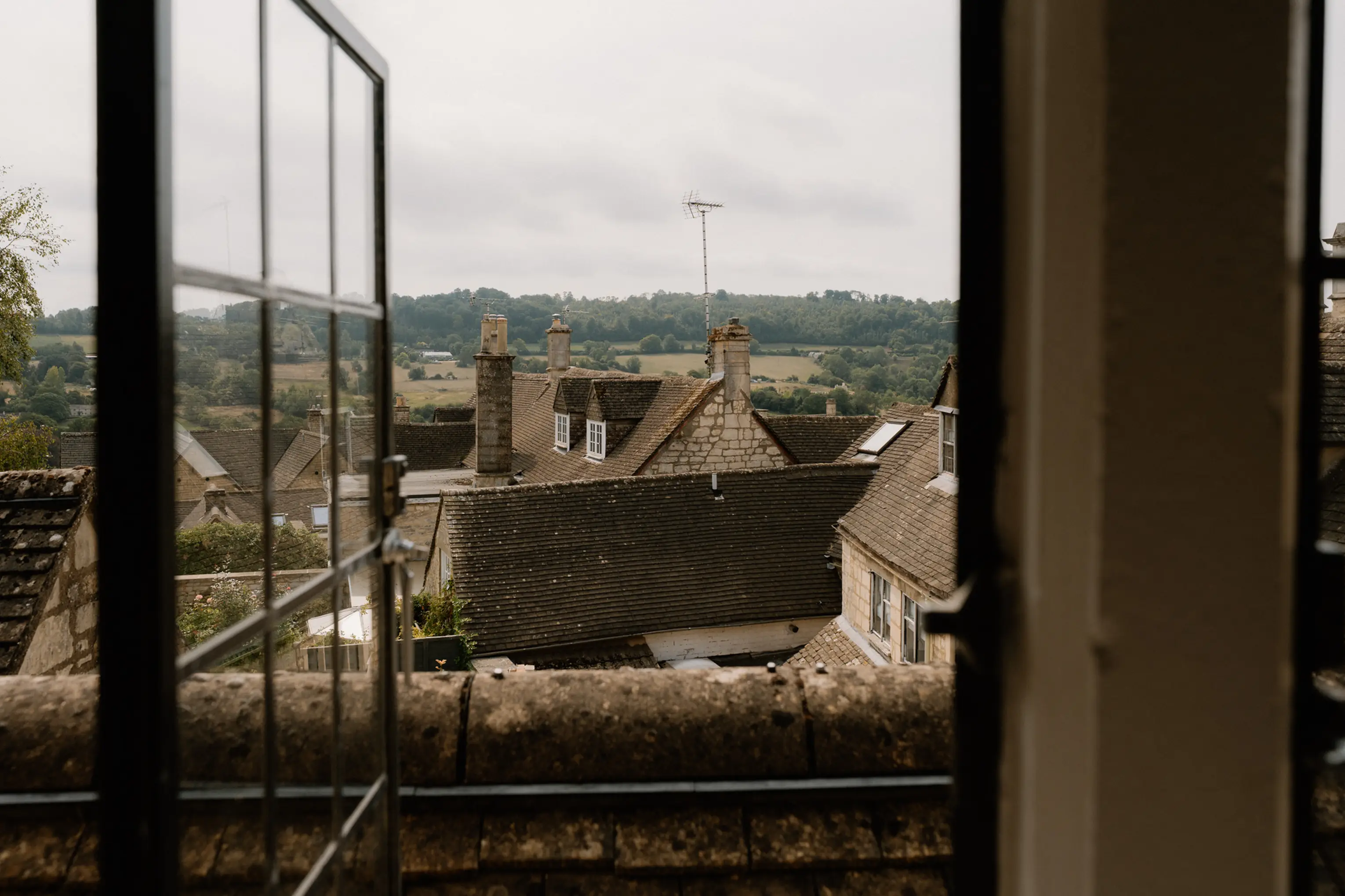 View over Cotswold rooftops and hills from a glass-framed window at ARC Painswick