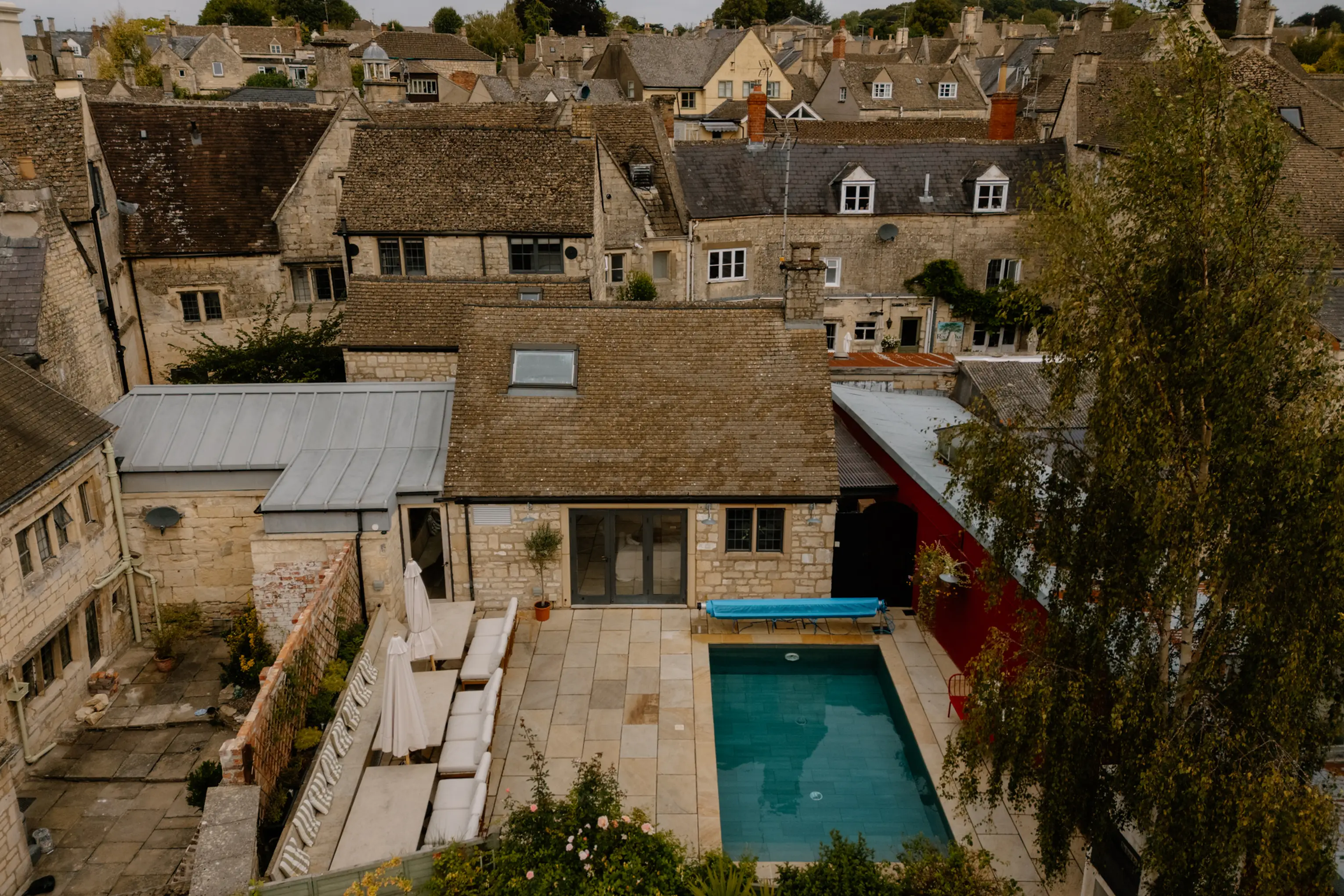 Aerial view of the internal courtyard and outdoor pool at ARC Painswick among Cotswold rooftops