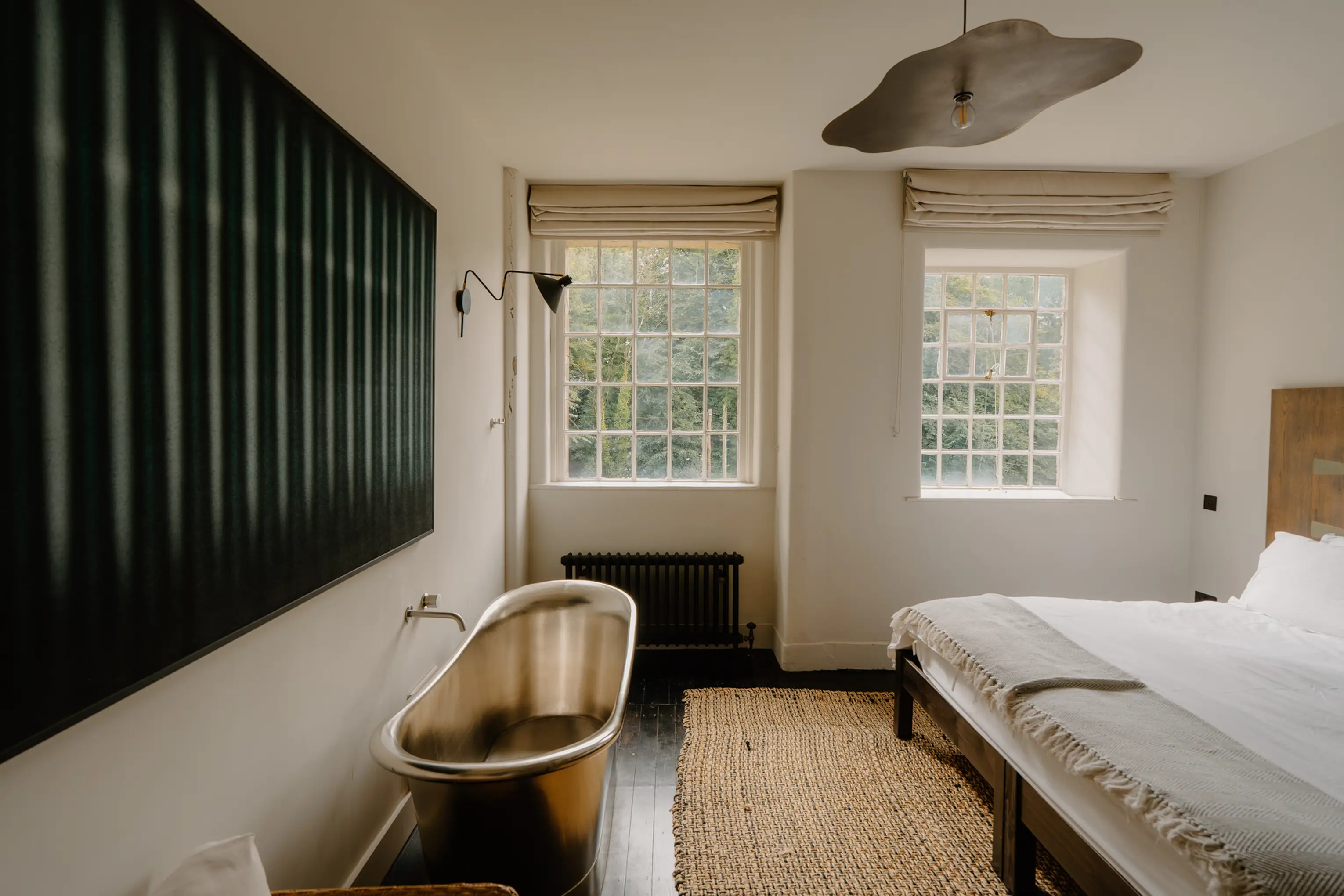 Bedroom at a Peaks with a freestanding copper bath, a dark green artwork and tall windows