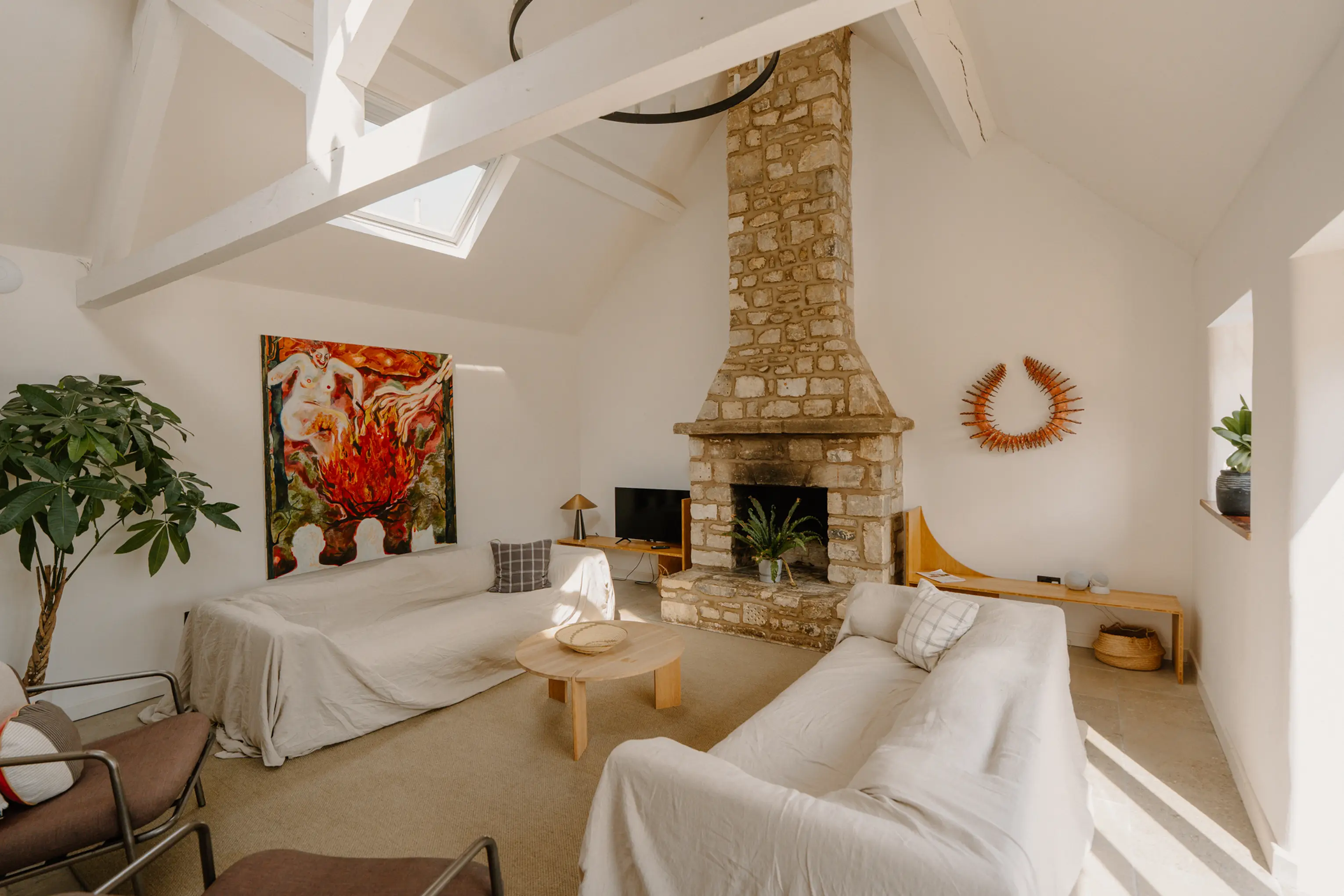 Living room at ARC Painswick with white sofas, a stone fireplace and a high ceiling