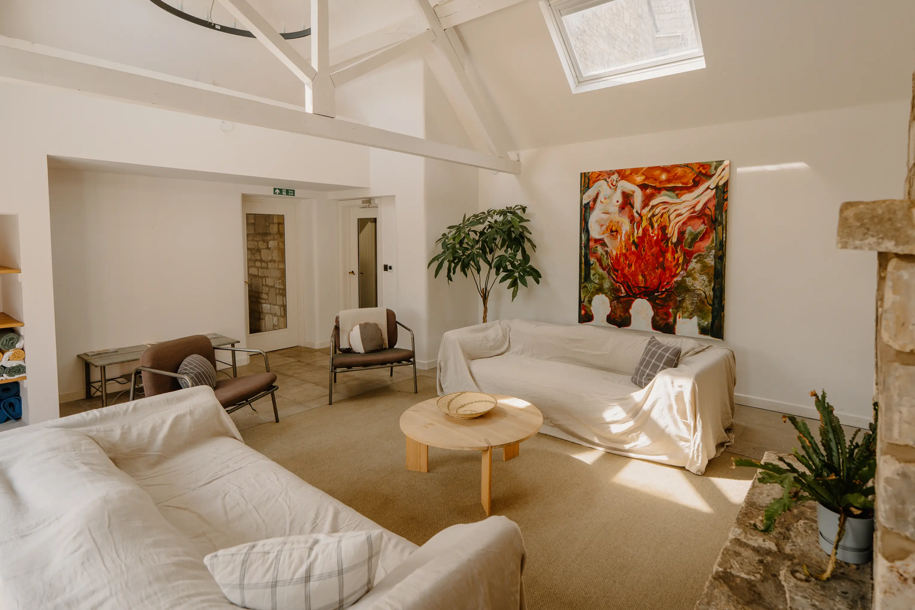 Lounge at ARC Painswick with white sofas, a skylight and bold artwork