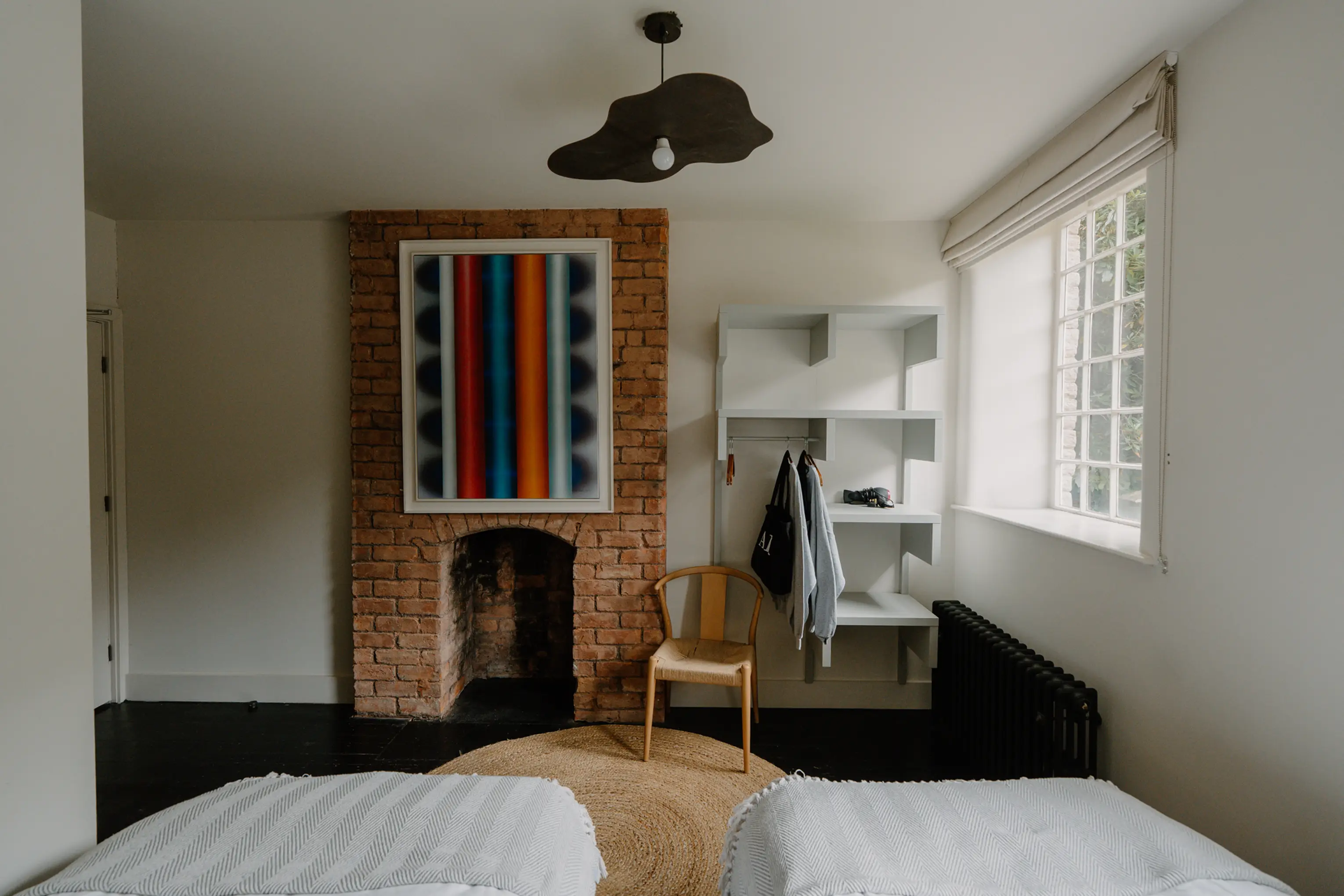Twin bedroom at ARC Peaks with an exposed brick fireplace, artwork and a window