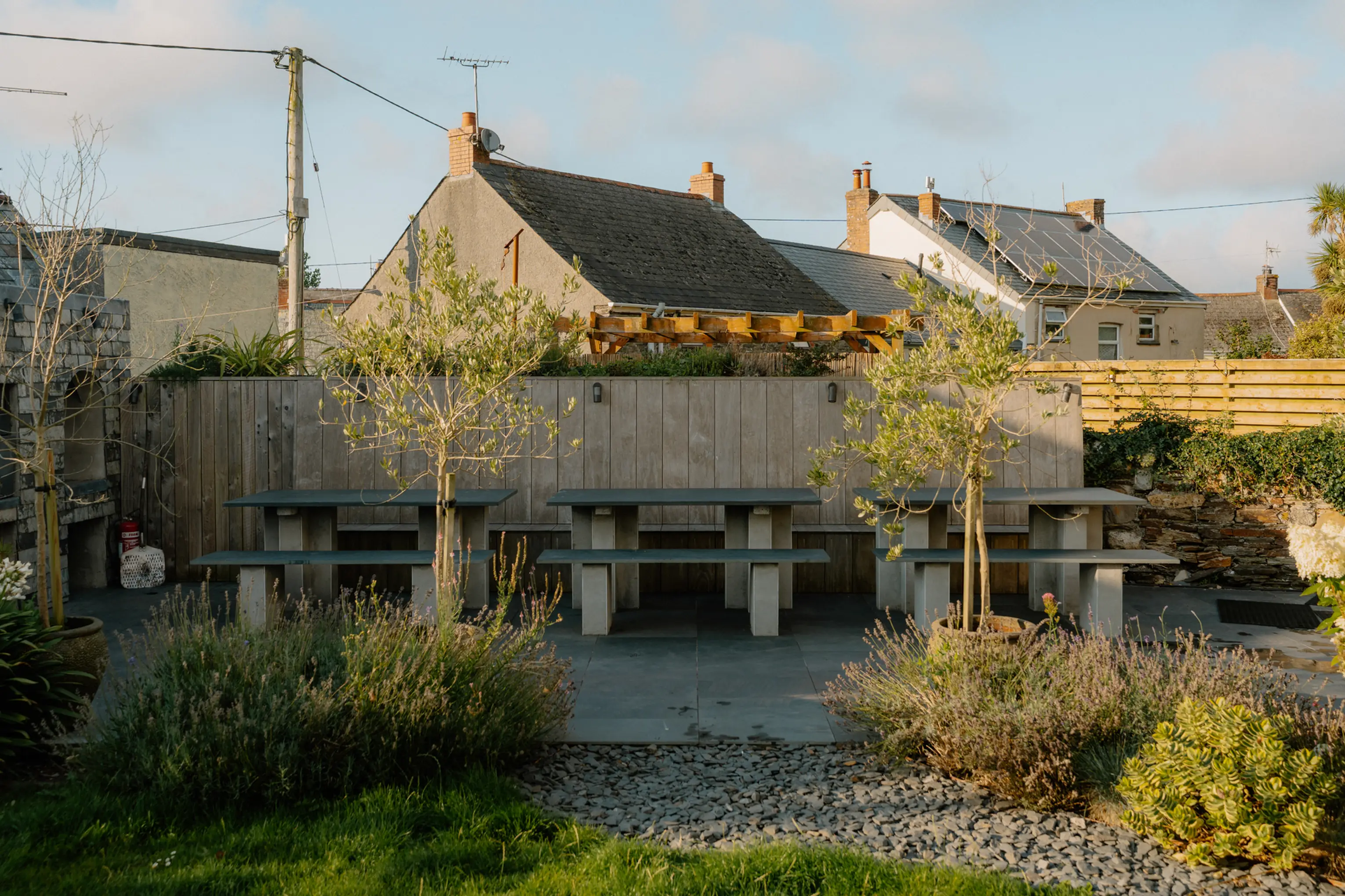 Gravel courtyard and large stone outdoor dining tables in the garden beside the stone buildings at ARC Padstow