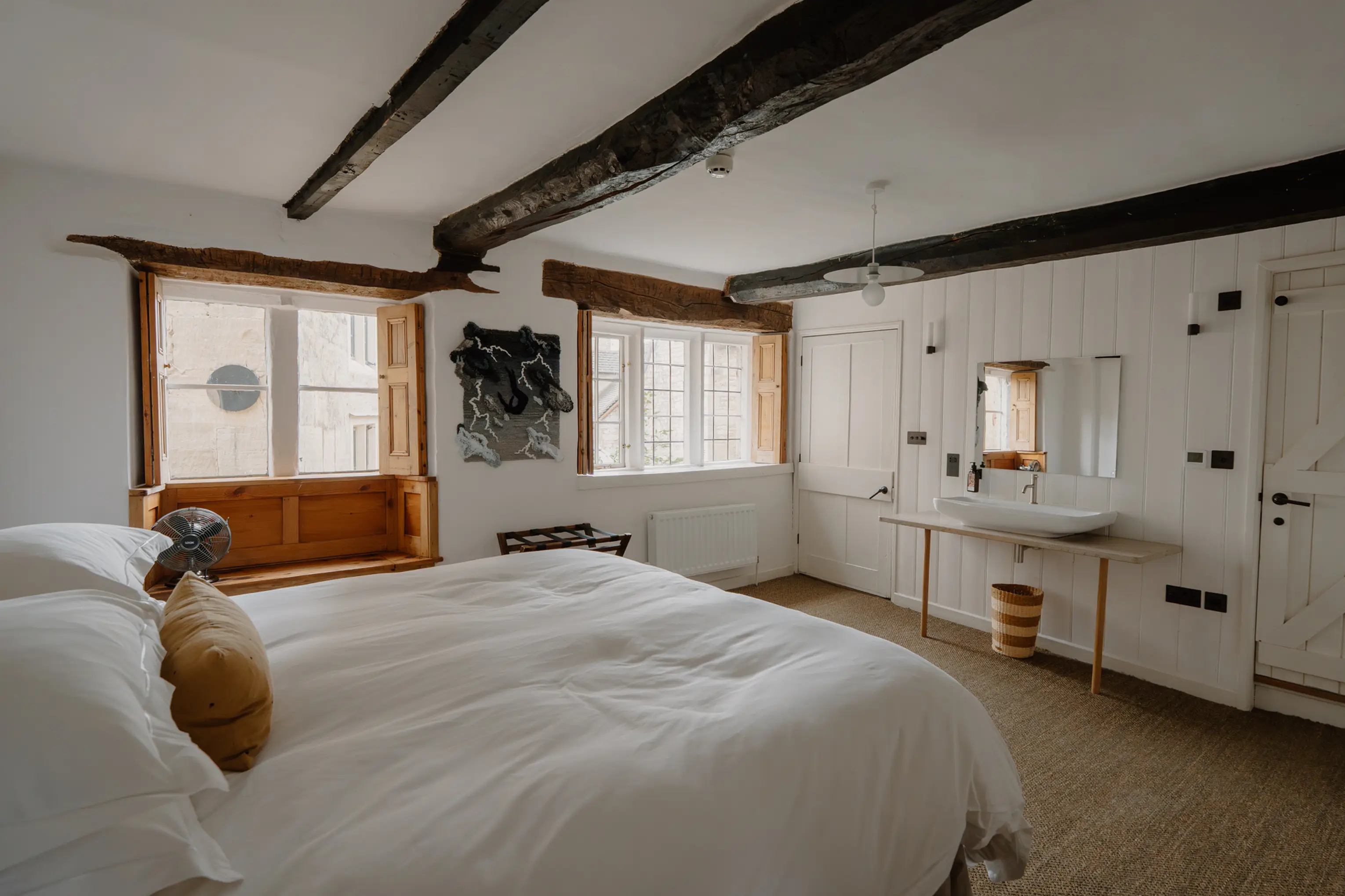 Superking bedroom at ARC Painswick with exposed beams and an open ensuite basin
