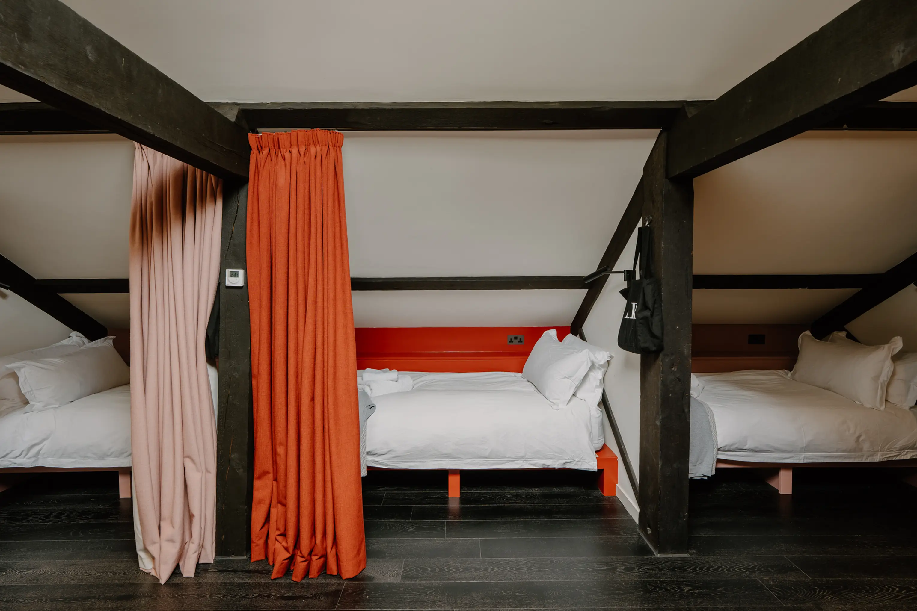 Attic dorm room bedroom at ARC Peaks with red curtains and exposed beams