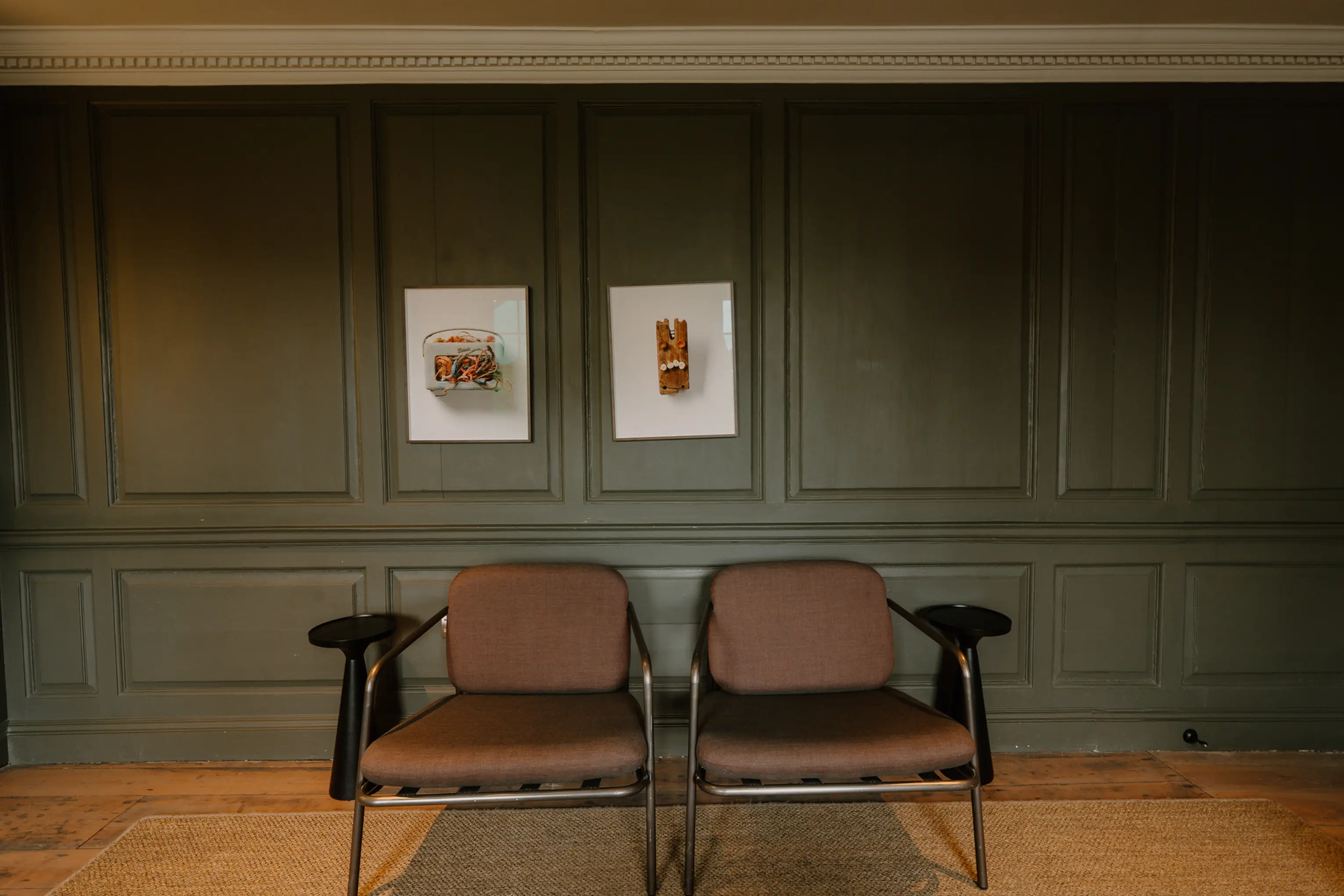 Pair of armchairs and framed artwork against a green wall in a sitting area at ARC Padstow