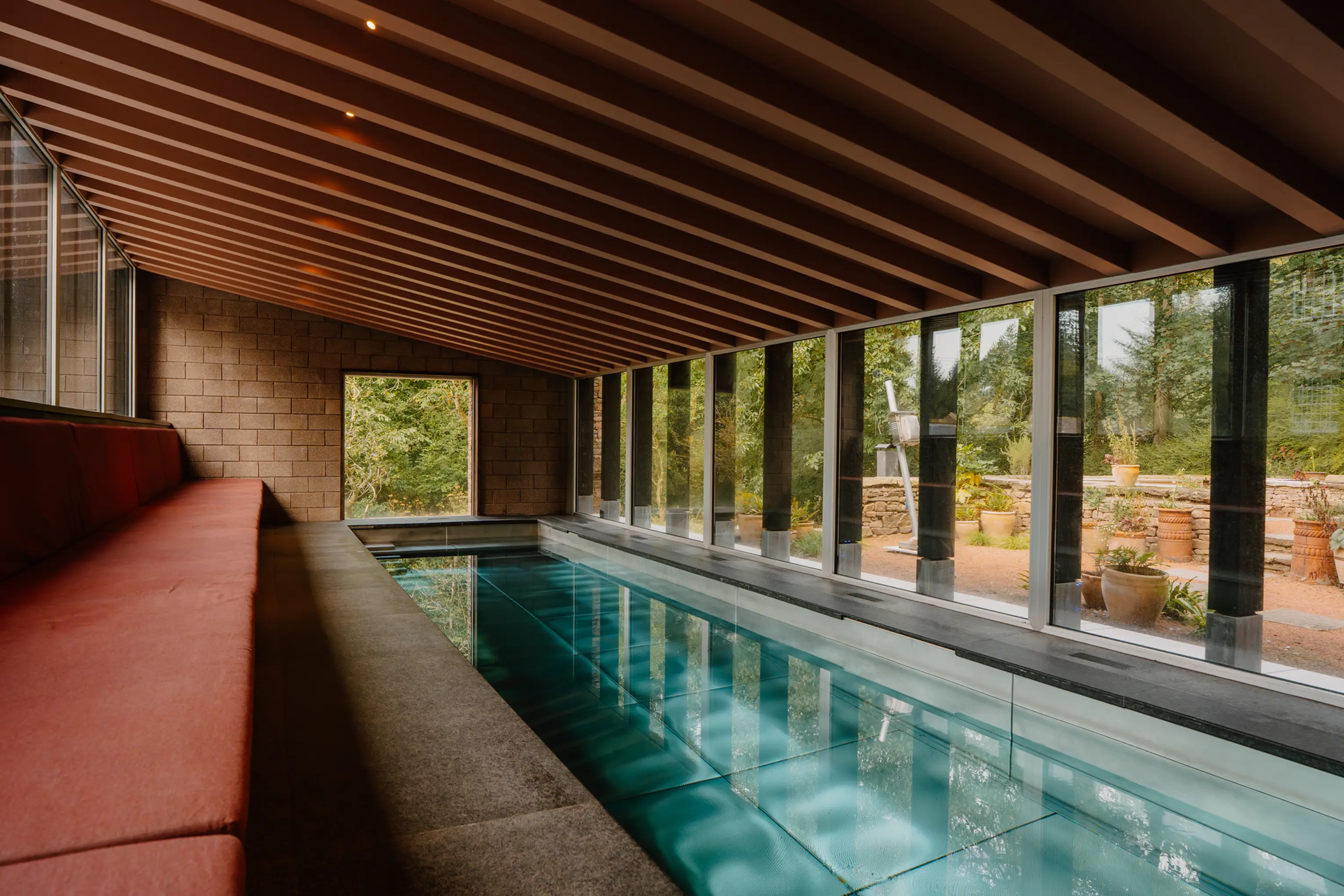 Indoor pool at ARC Peaks with a timber ceiling, red bench and a glazed garden wall