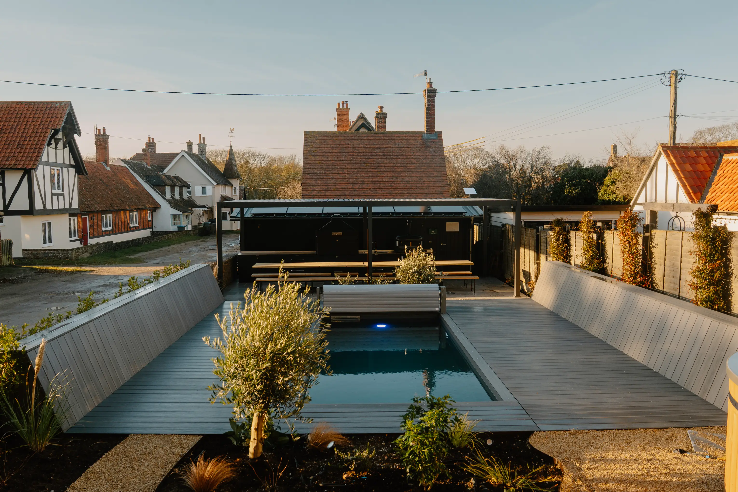 Outdoor pool at ARC Thorpeness with the converted water tower and Suffolk village behind at dusk