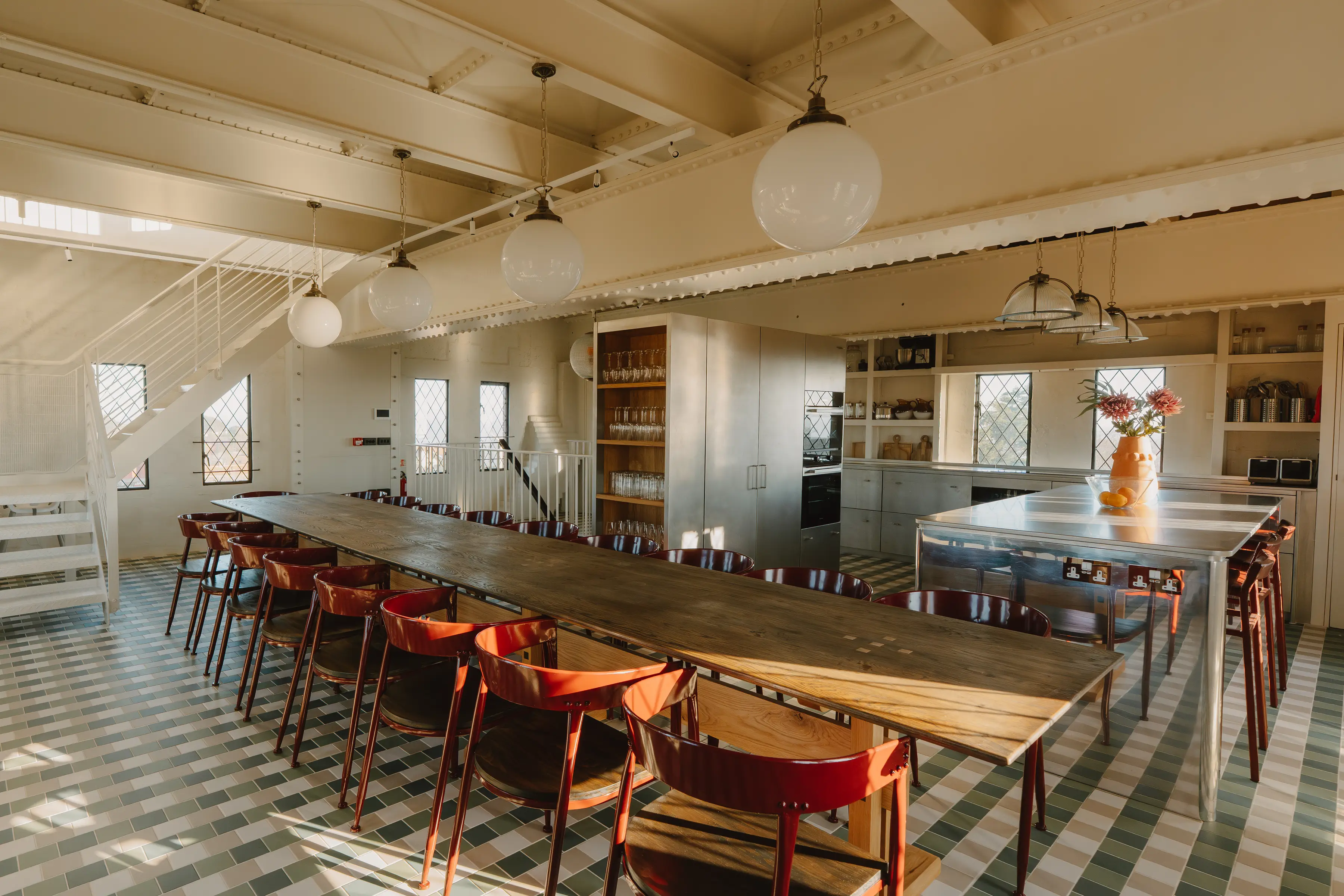 Dining room at ARC Thorpeness with long tables, red and timber chairs and a patterned floor