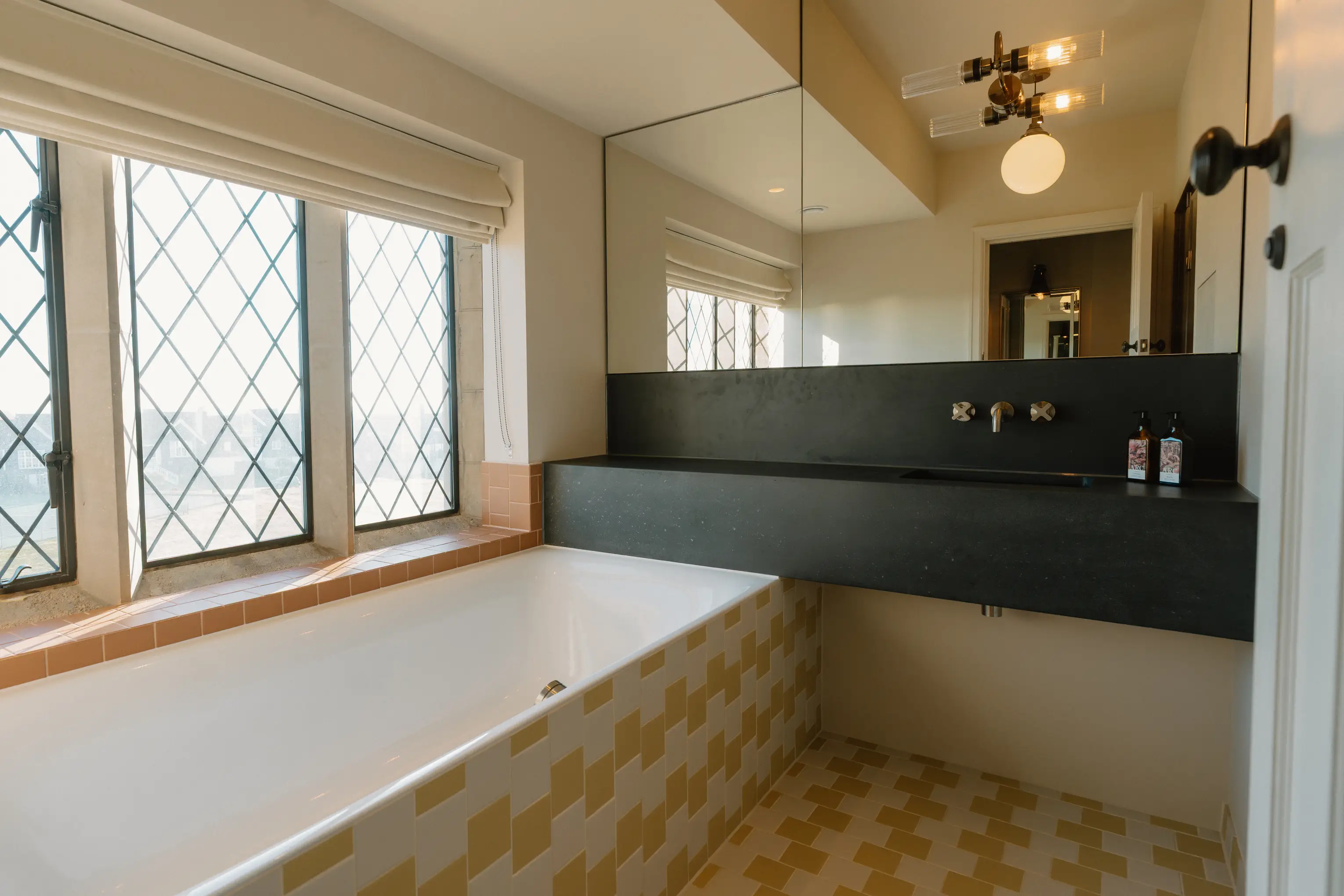 Ensuite at ARC Thorpeness with a dark vanity, mirror and a leaded window