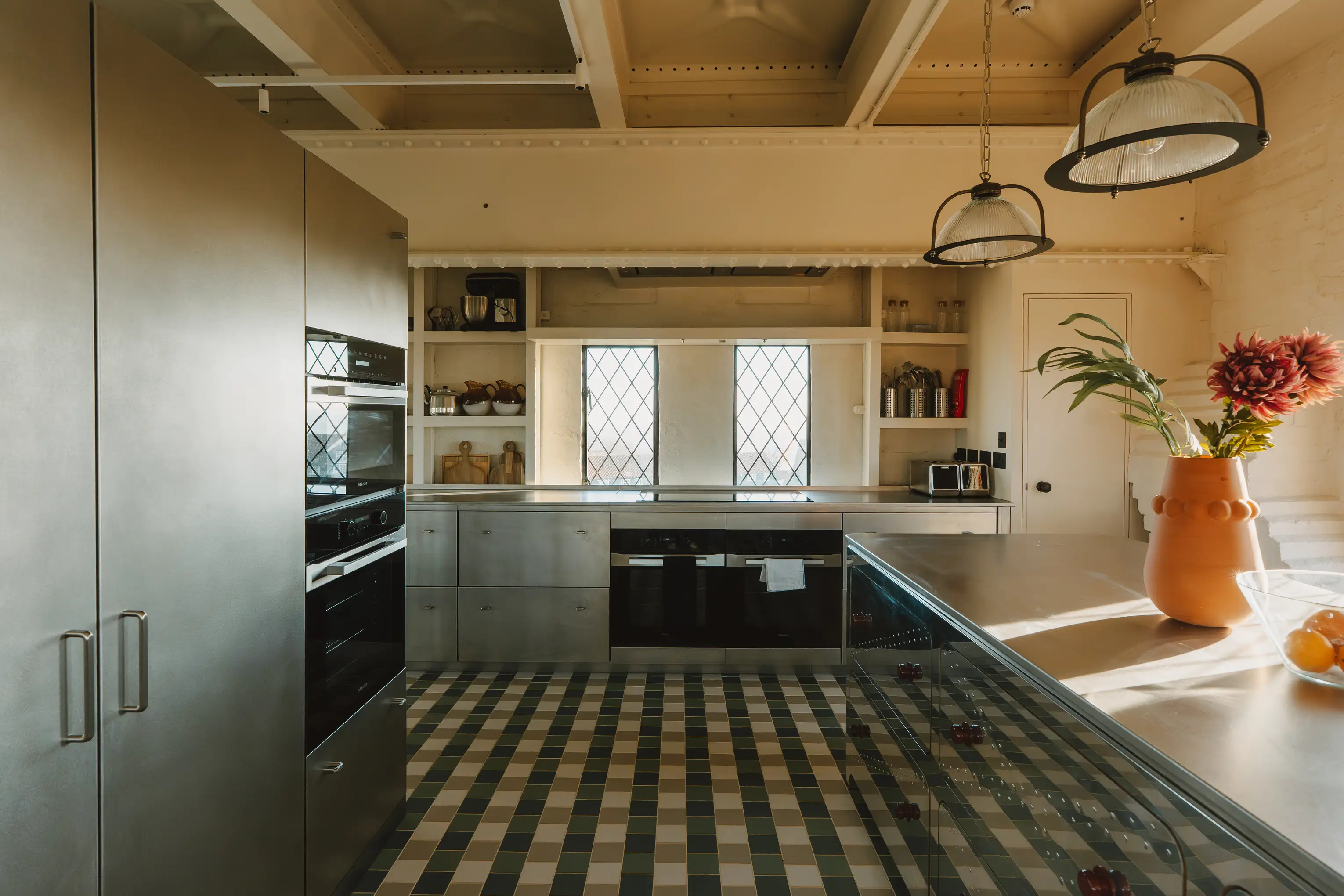 Kitchen at ARC Thorpeness with a steel counter, green tiled floor and Miele appliances