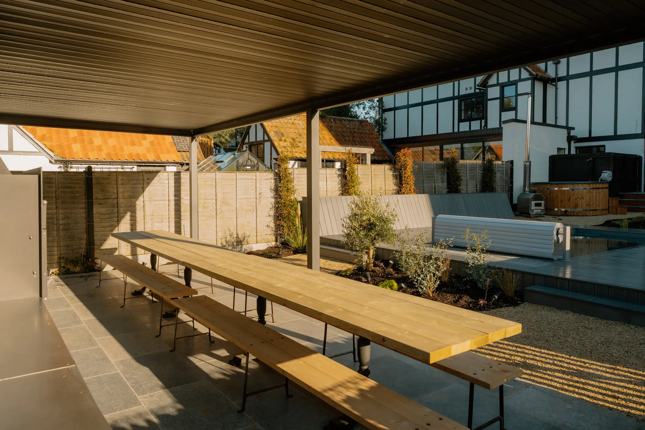 A contemporary pergola houses the alfresco kitchen and bespoke dining table