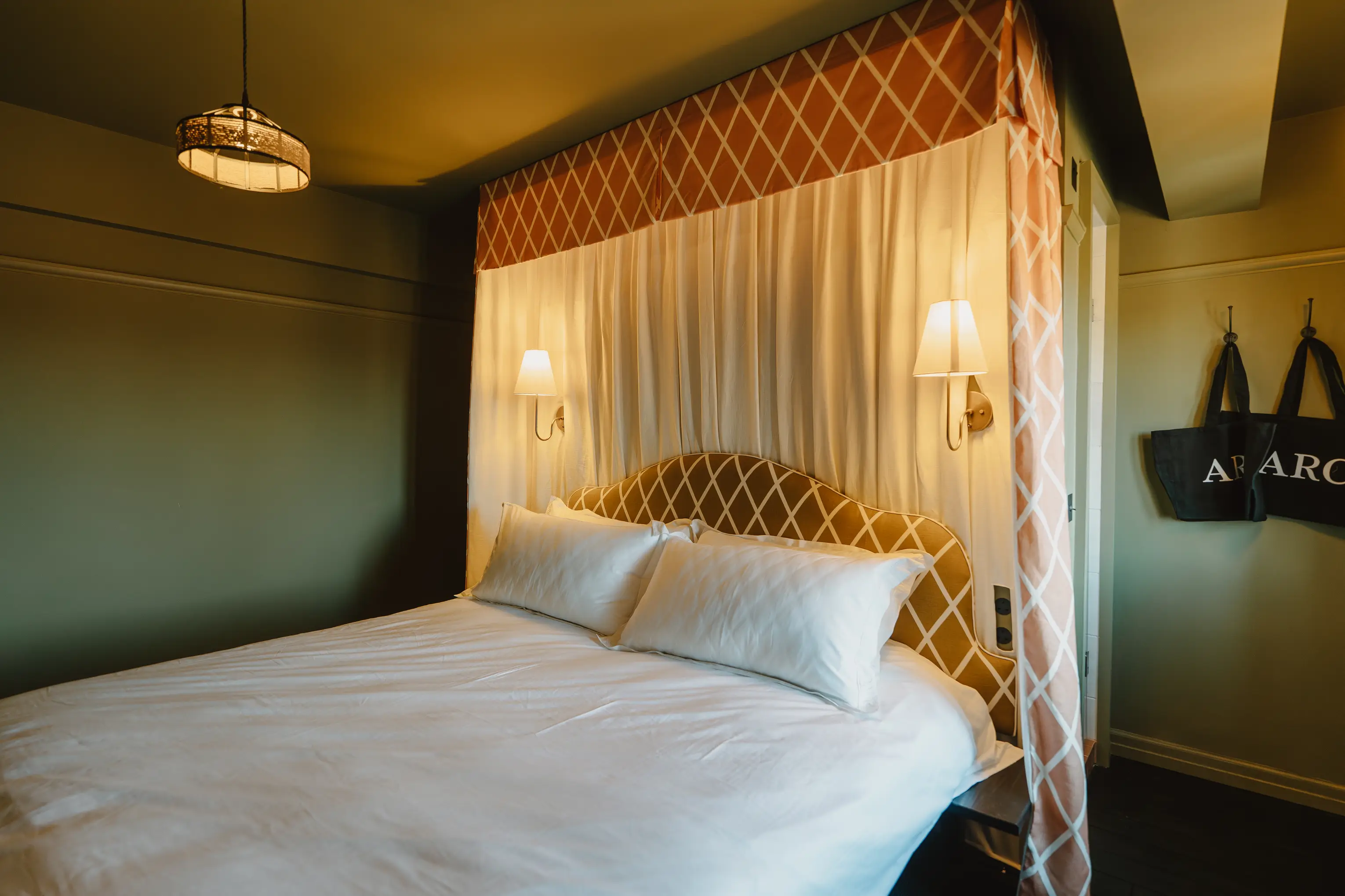 Bedroom at ARC Thorpeness with a bed against a patterned yellow canopy and wall lights