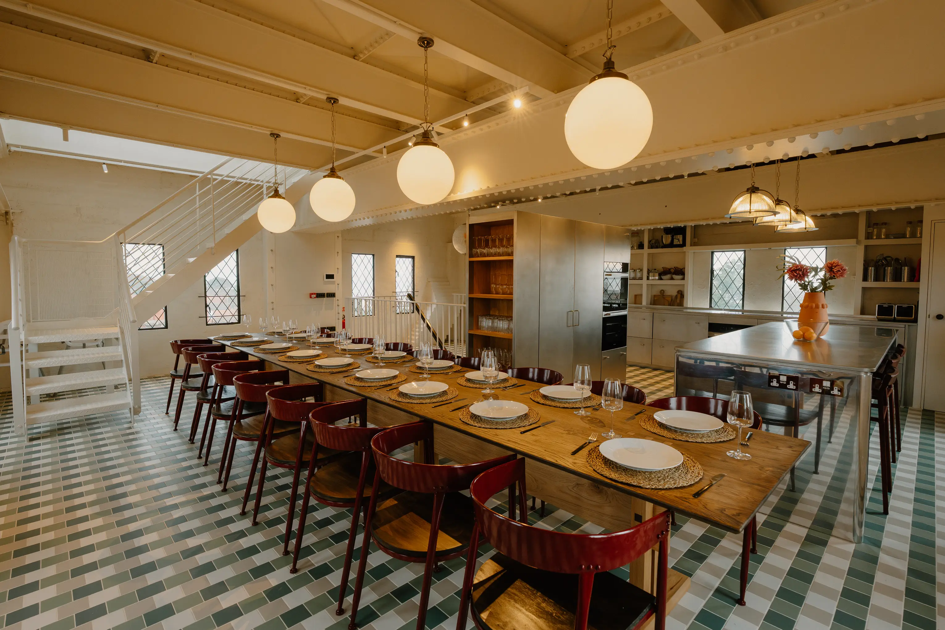 Dining room at ARC Thorpeness with long tables, red and timber chairs and a patterned floor