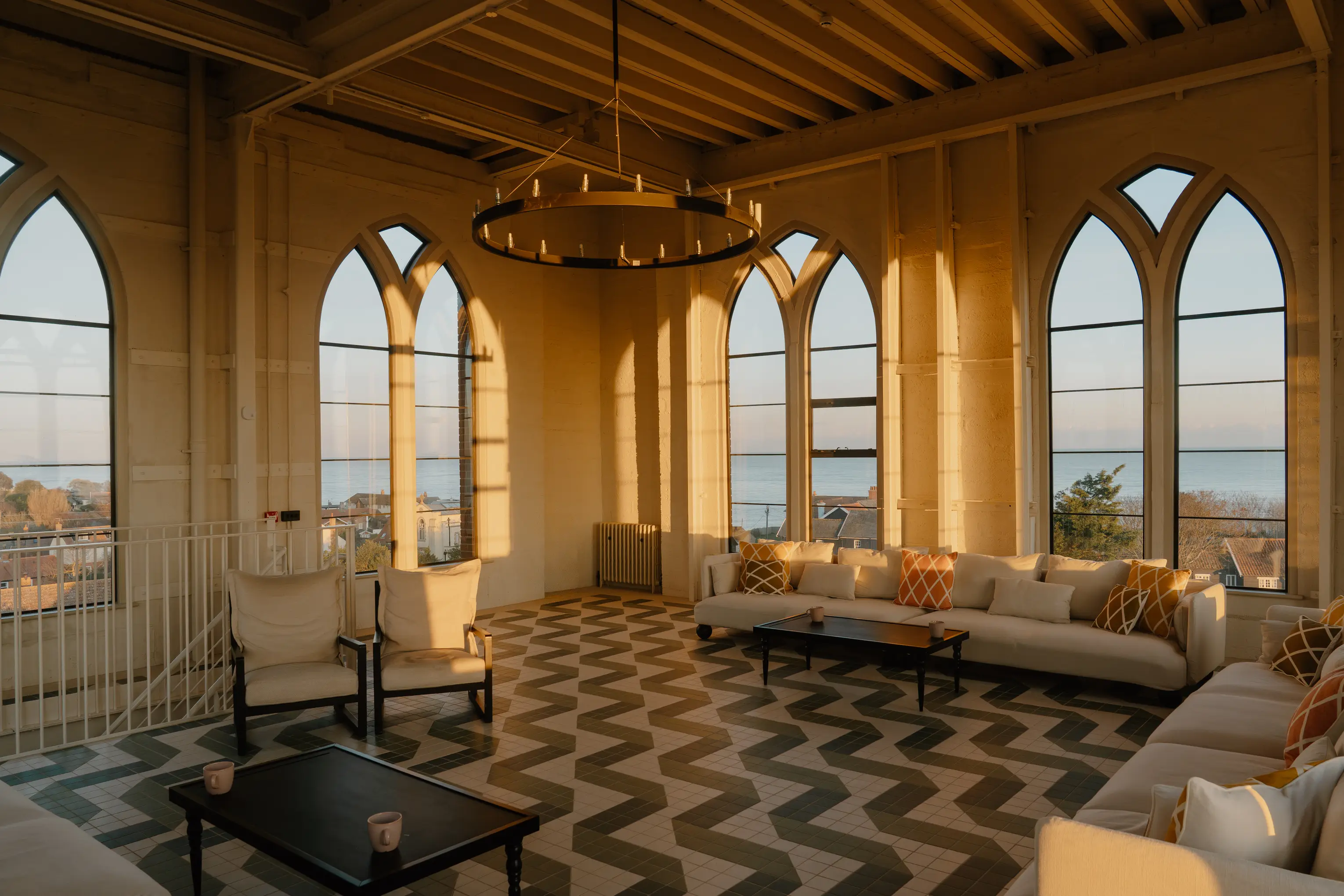 Top-floor lounge at ARC Thorpeness with arched windows, sofas and coastal light
