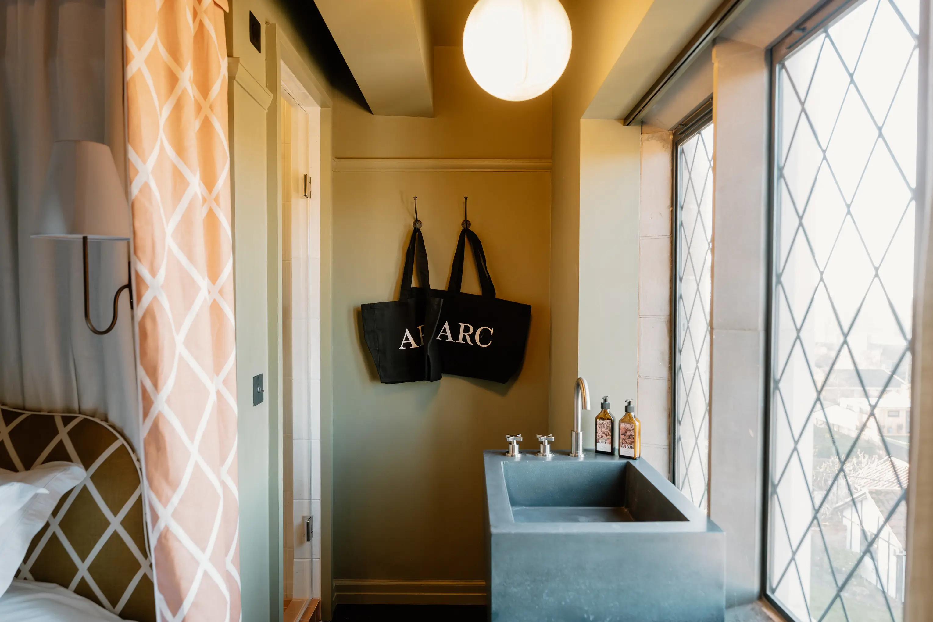 Bedroom corner at ARC Thorpeness with a basin, patterned wall and ARC tote bags