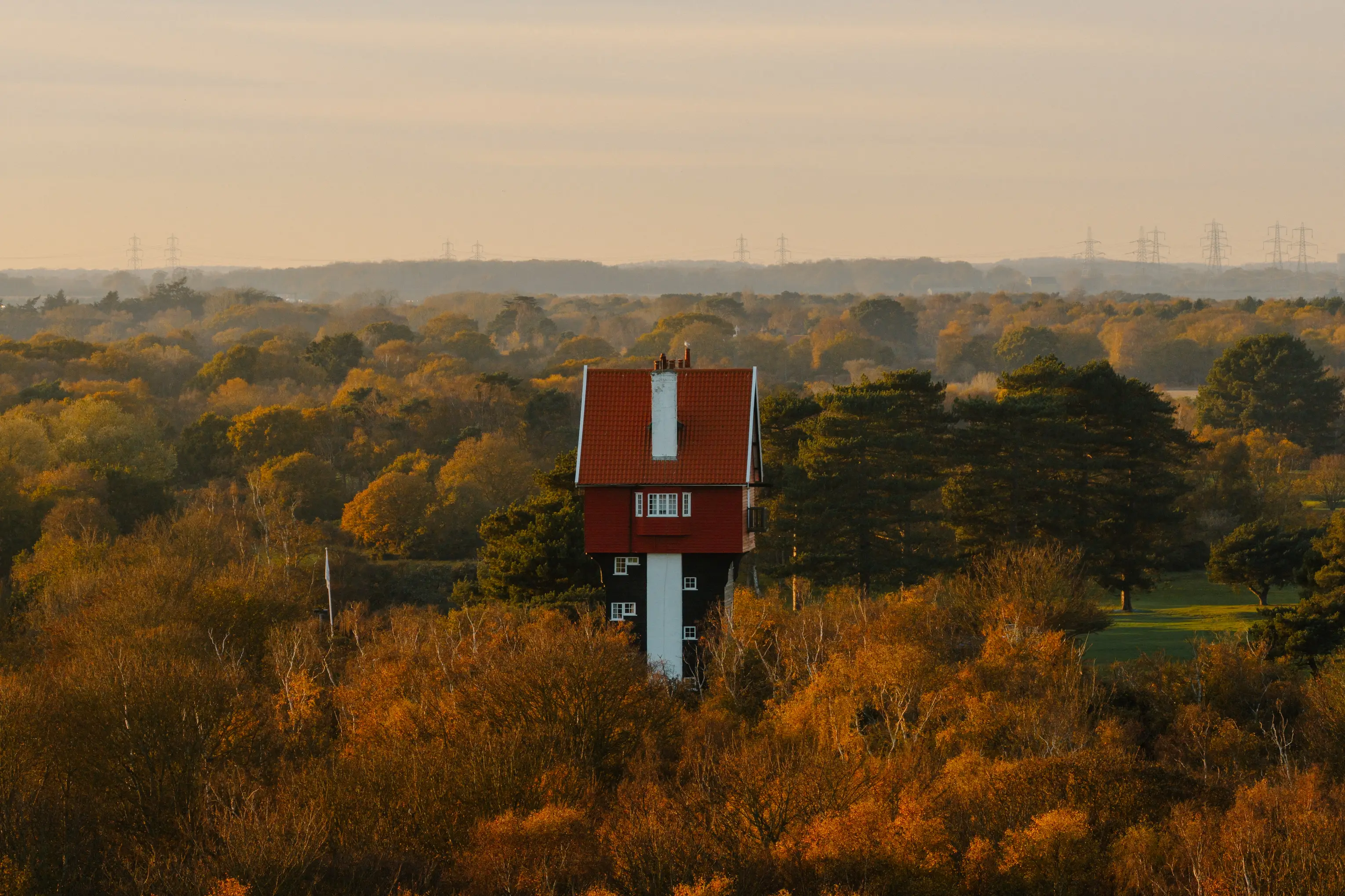 Aerial view over the Thorpeness heath and woodland with the water tower beyond in autumn
