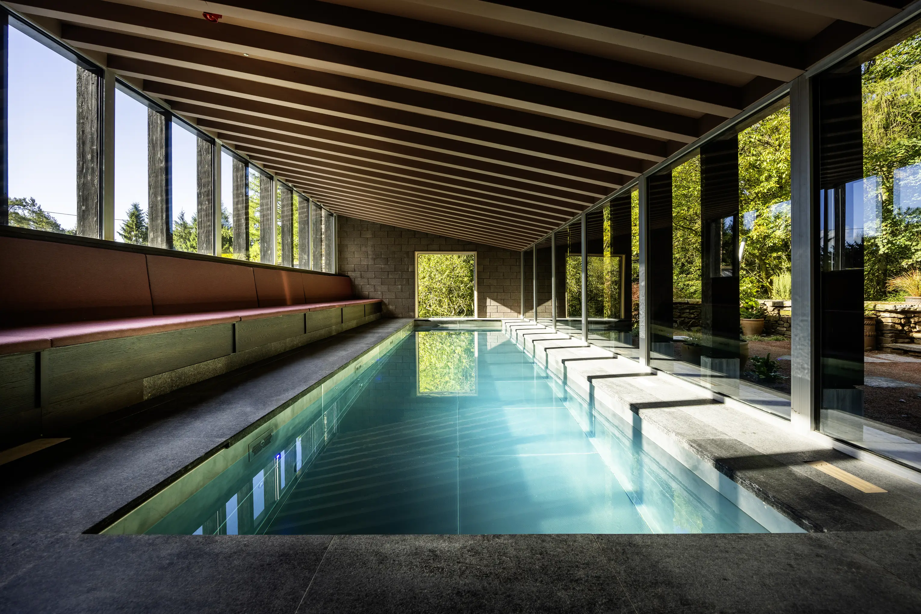 The 12 metre indoor pool at ARC Peaks beneath a timber ceiling, with a glazed wall onto the garden
