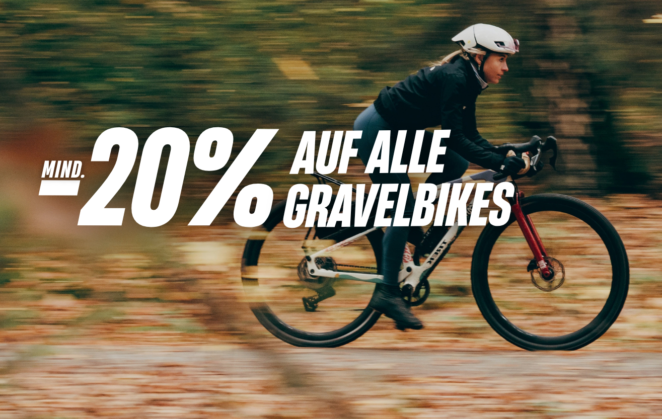 Frau auf einem Gravelbike fährt über einen Waldweg. Rabattaktion: „Mindestens 20 % auf alle Gravelbikes“