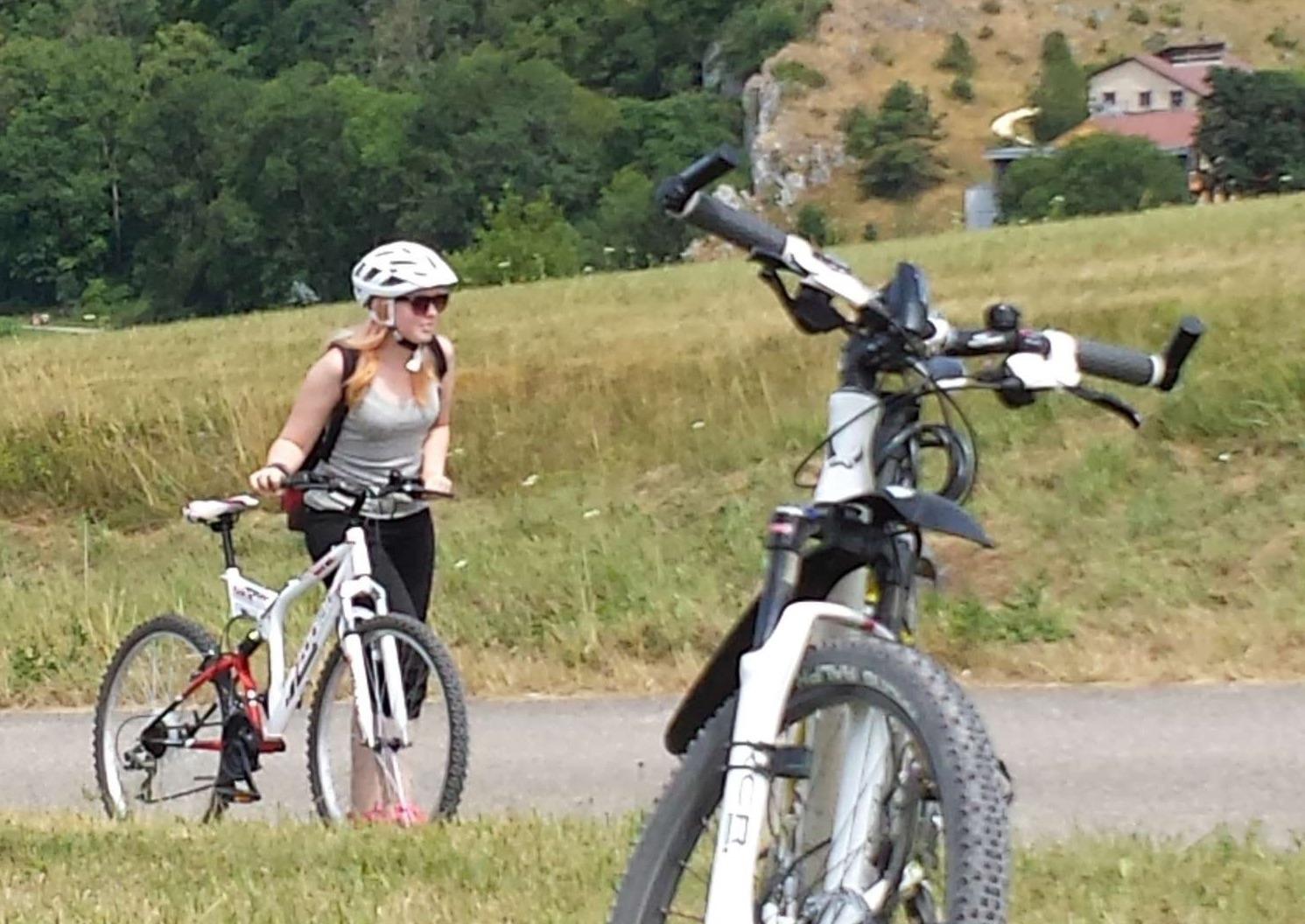 Frau schiebt Fahrrad einen Berg hoch