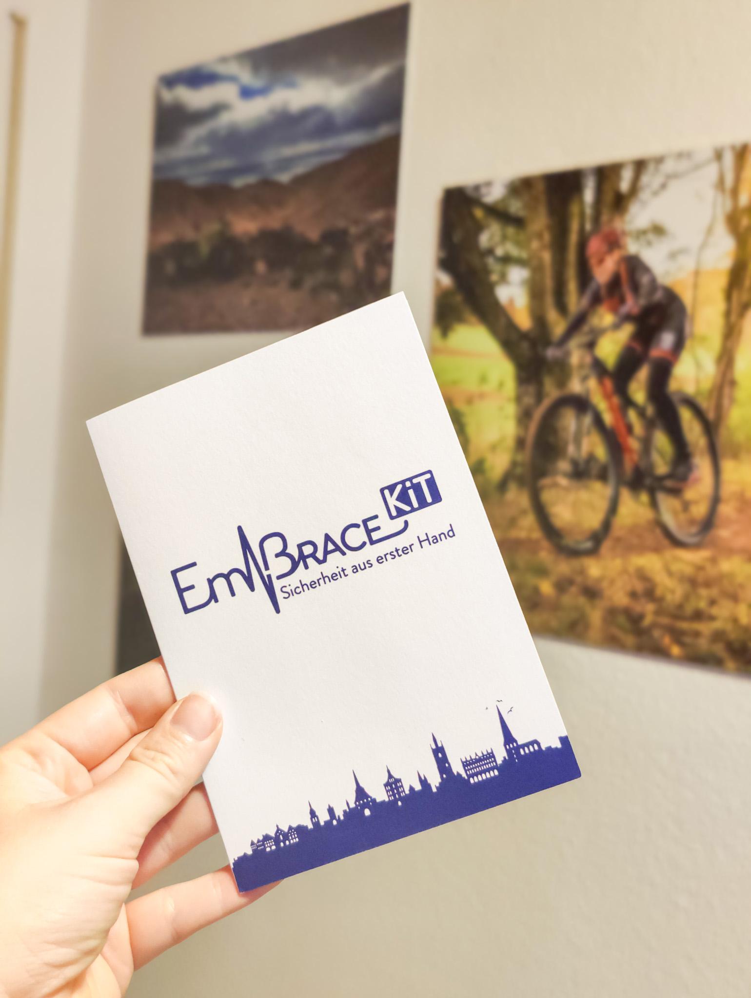 Hand hält das Embrace Kit - im Hintergrund Fahrradfotos