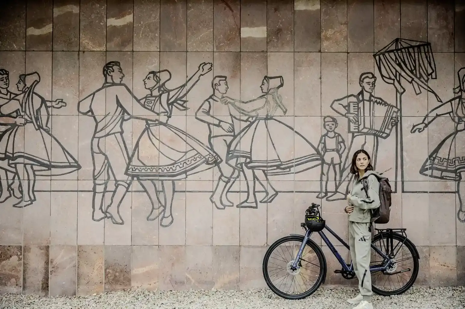 Frau steht mit ihrem Citybike vor einer  Wand im Freizeitlook.