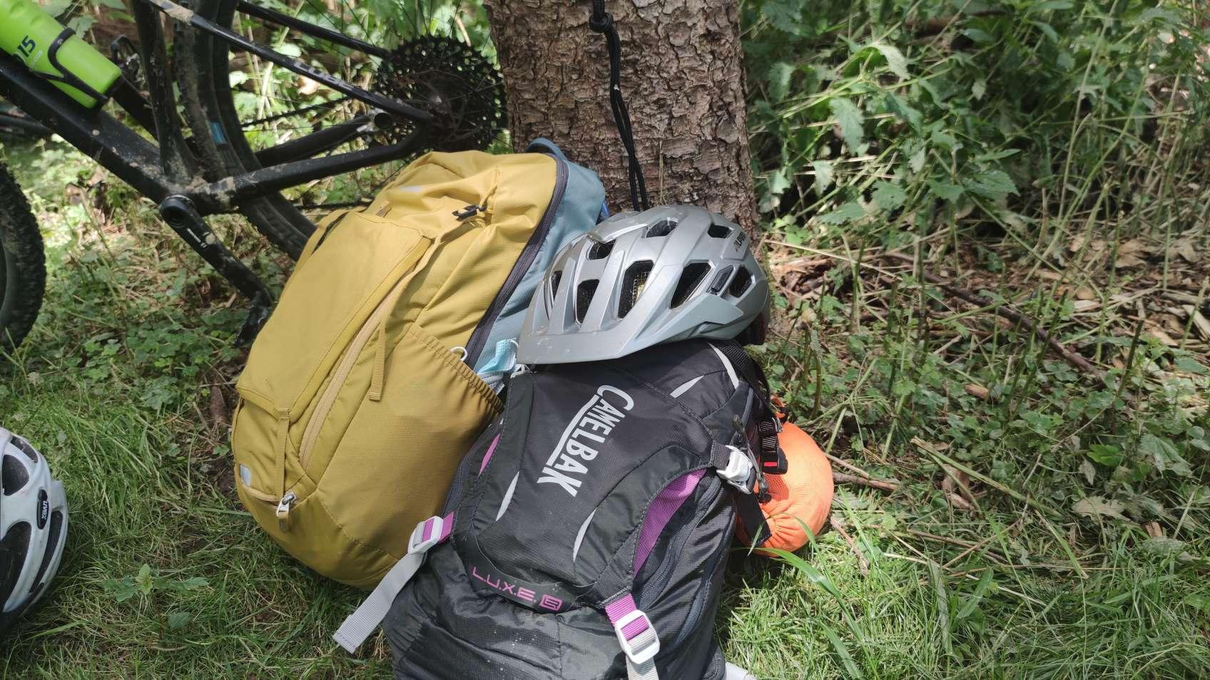 Fahrradhelm liegt im Freien auf Rucksäcken und ist Wetterbedingungen ausgesetzt.