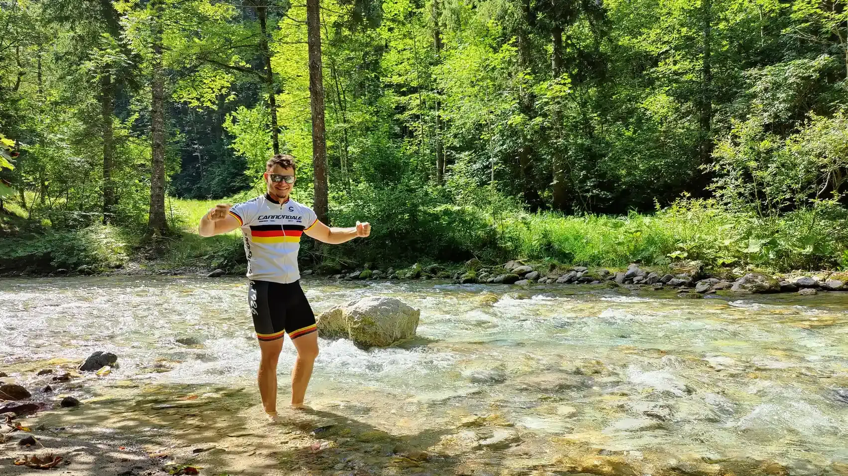 Radfahrer macht eine Pause am Bach und erfrischt sich mit kalten Wasser.