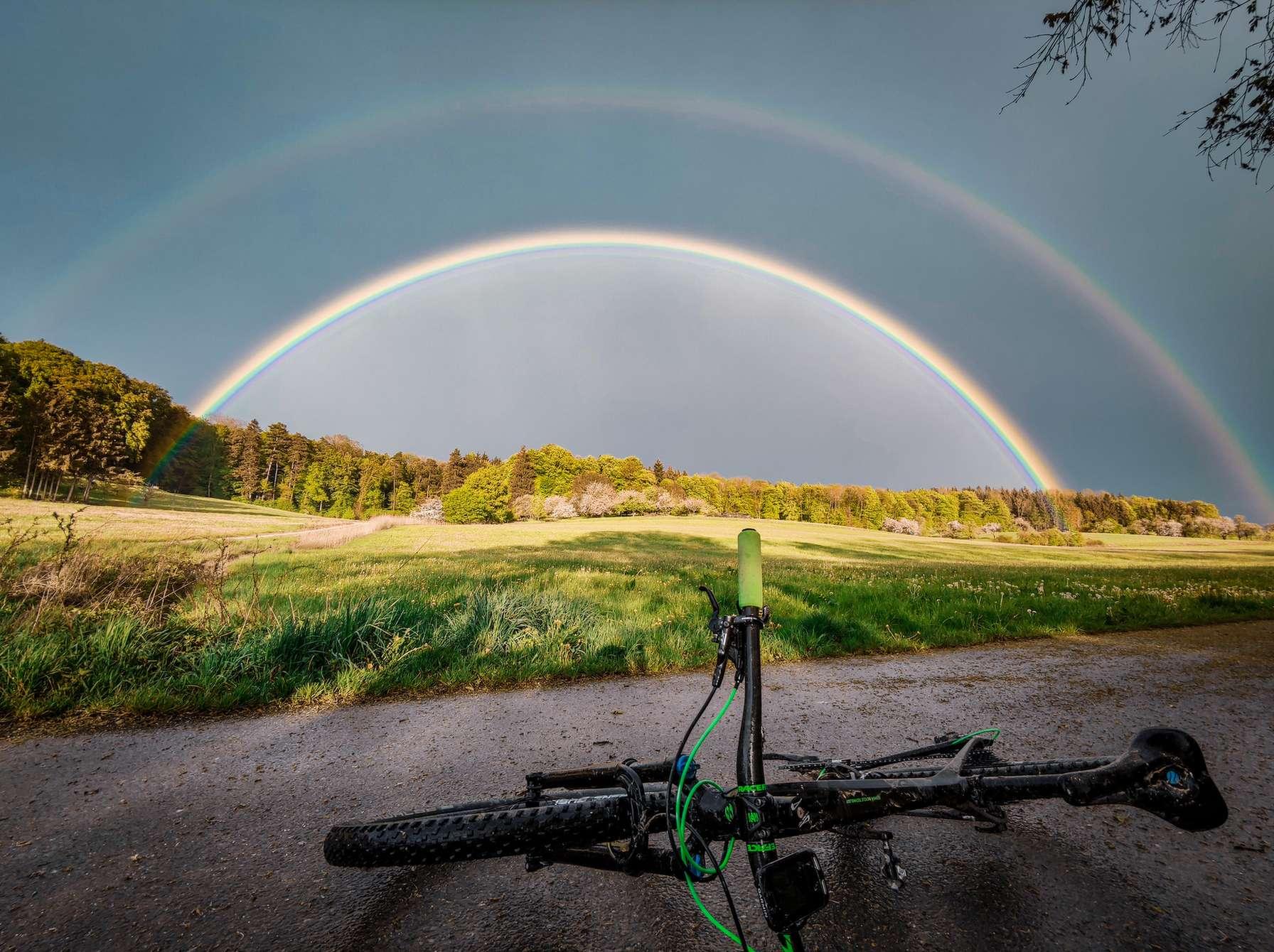 Doppelregenbogen im Hintergrund und ein Fahrrad im Vordergrund
