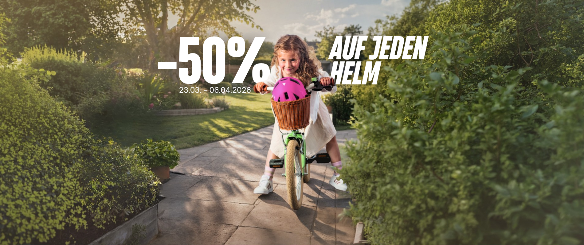 Mädchen auf Kinderfahrrad mit buntem Helm im Körbchen am Lenker