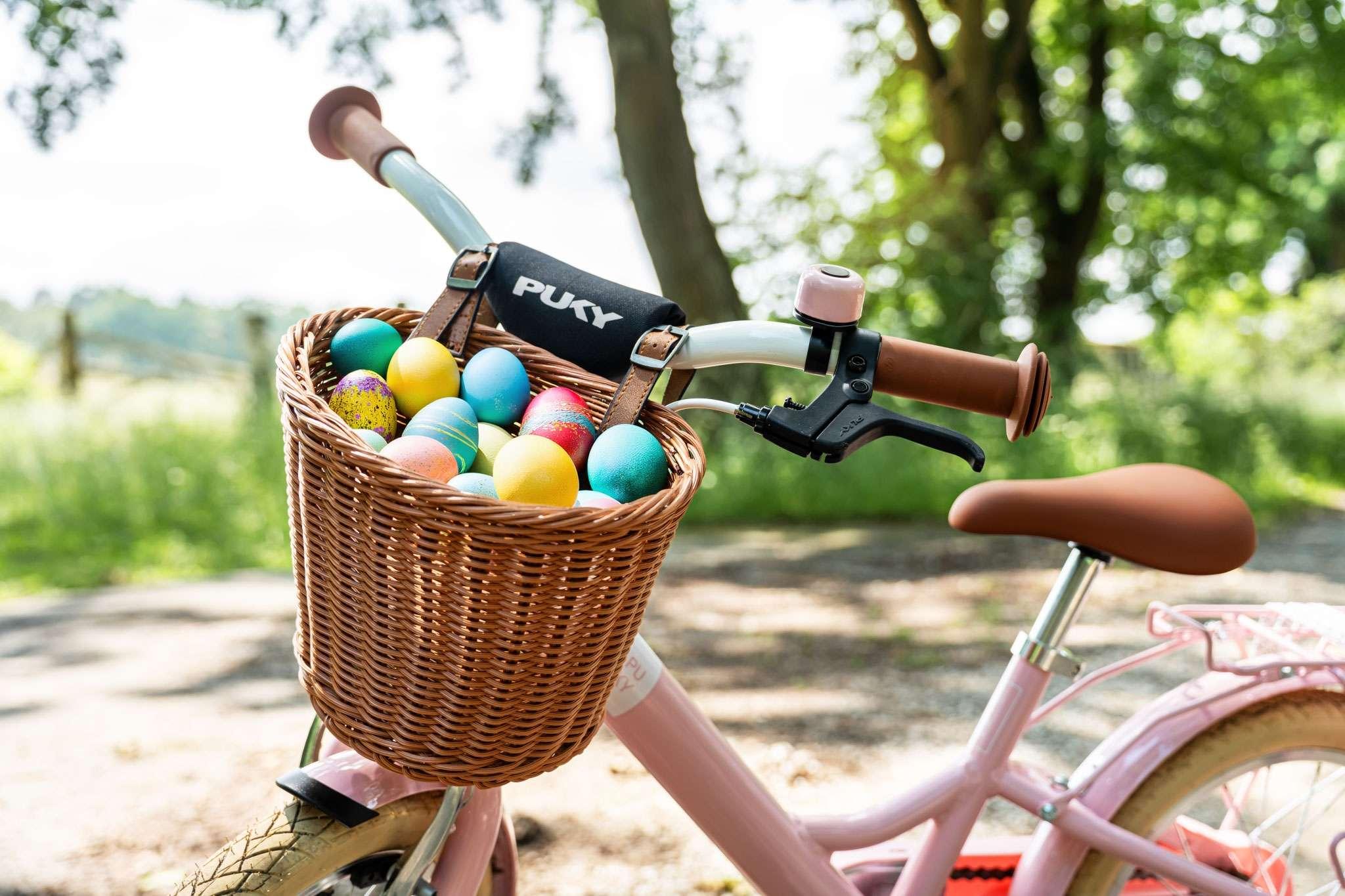 Ein Fahrrad mit einem Korb voller bunter Ostereier im Freien.
