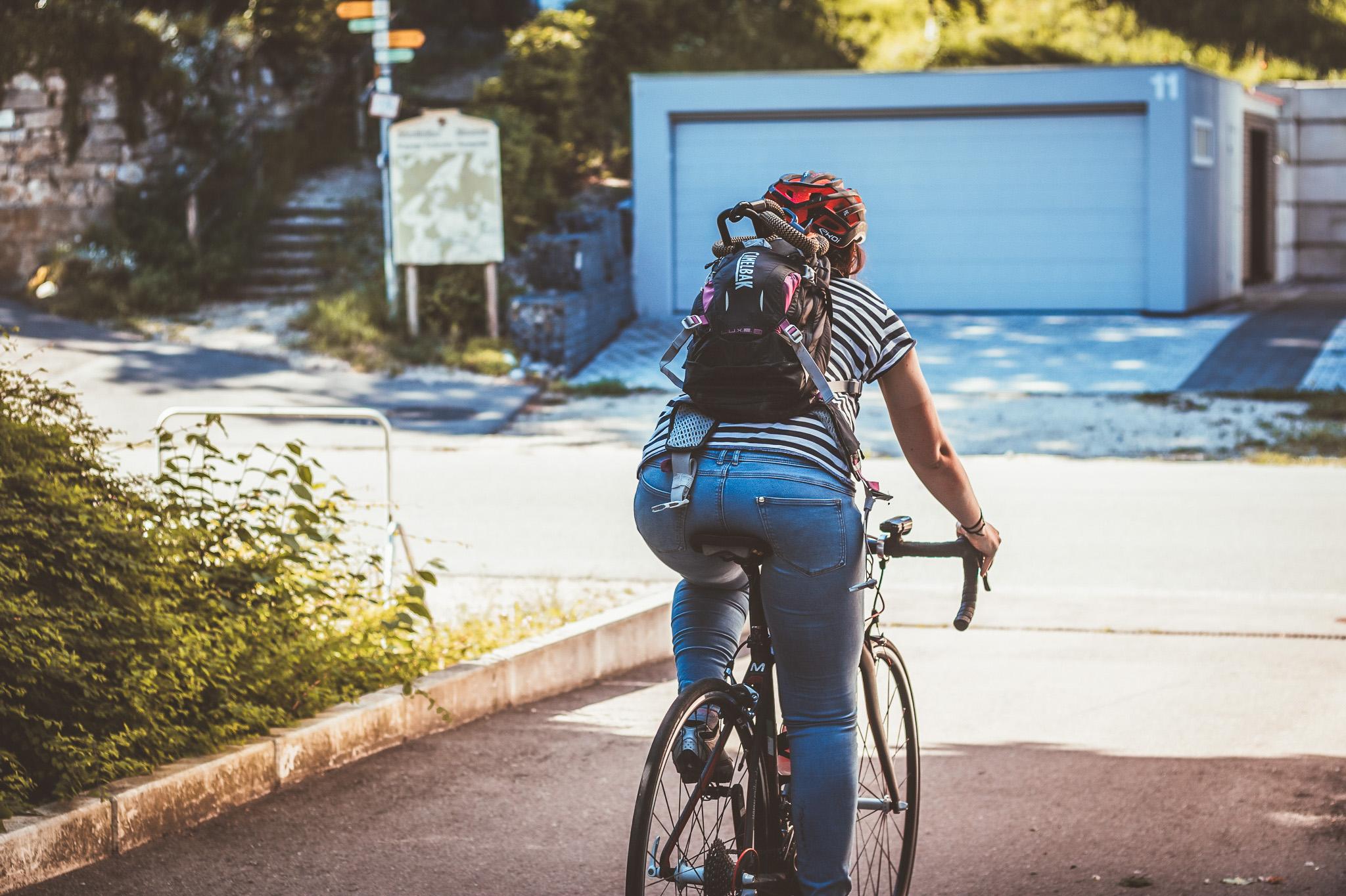 Frau auf dem Rennrad mit einem Rucksack auf dem Ruecken faehrt zum Einkaufen mit dem Fahrrad.