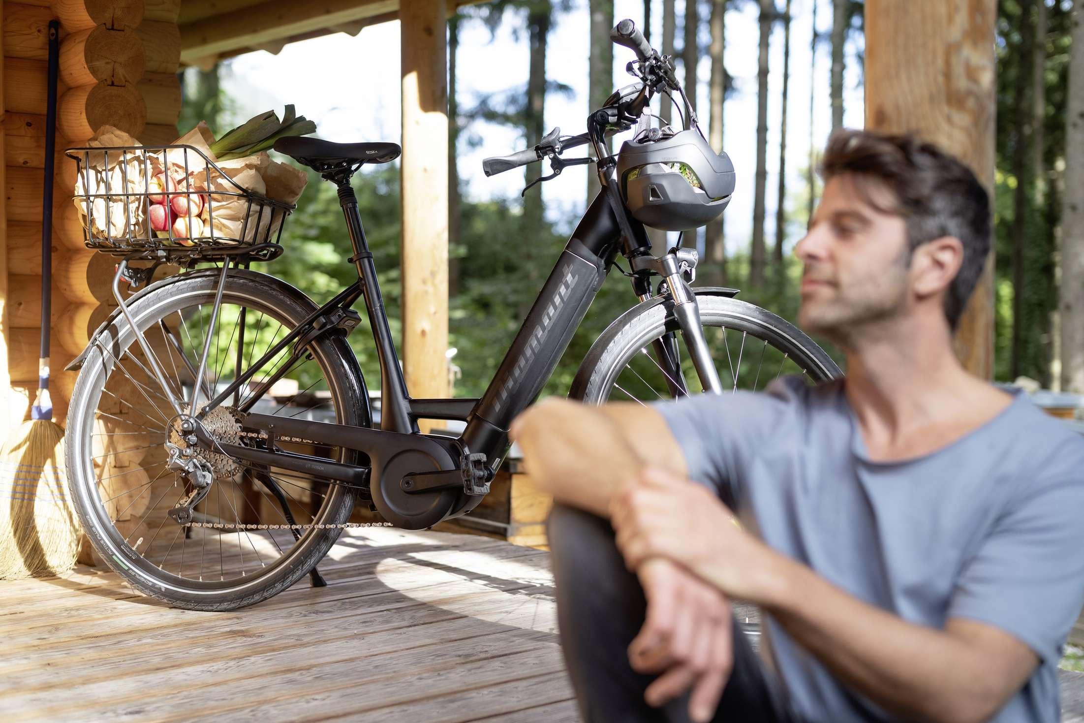 E-Bike mit Einkauf auf dem Gepäckträger - im Vordergrund ein Mann.