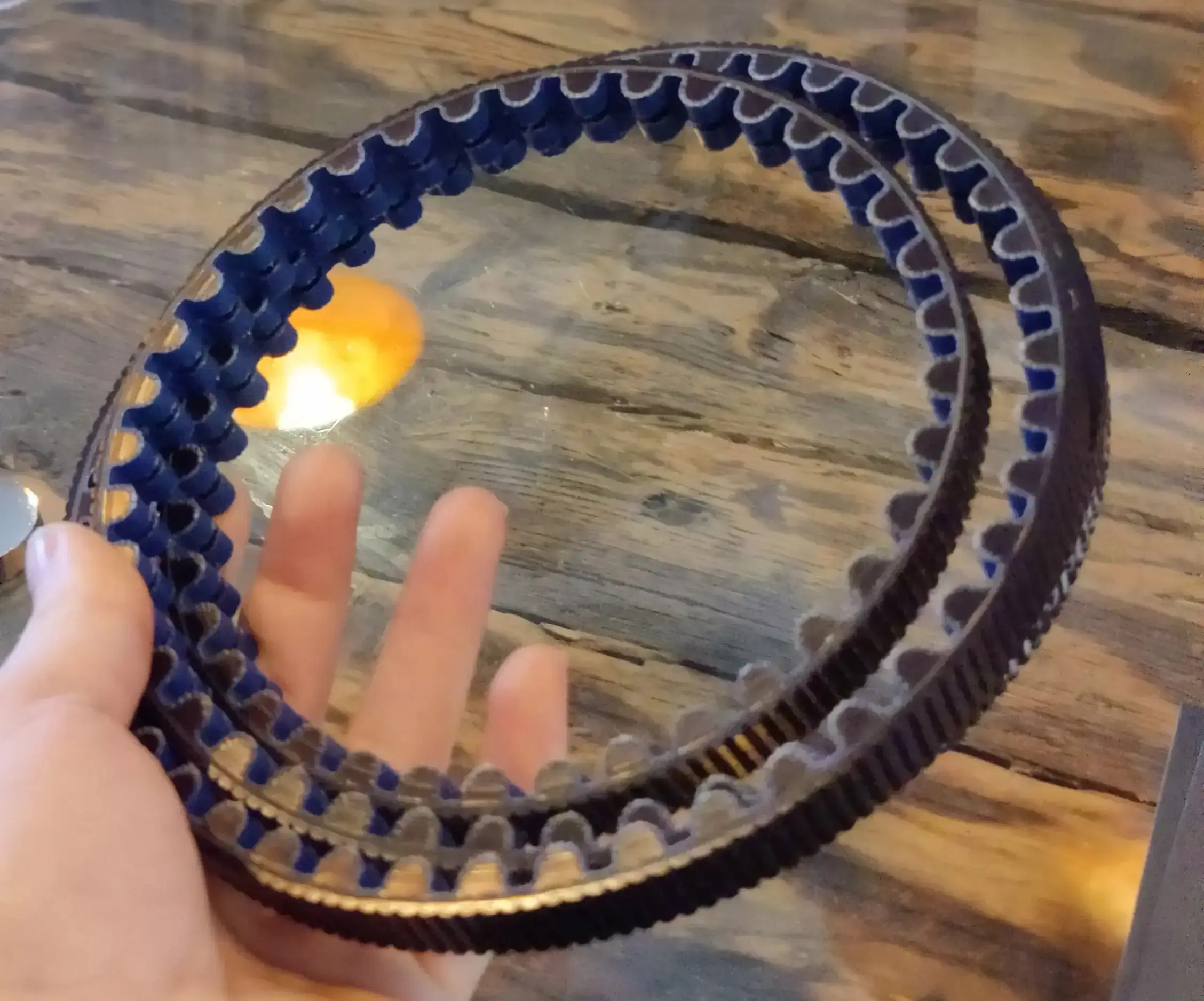 Eine Hand hält einen aufgerollten Riemenantrieb.