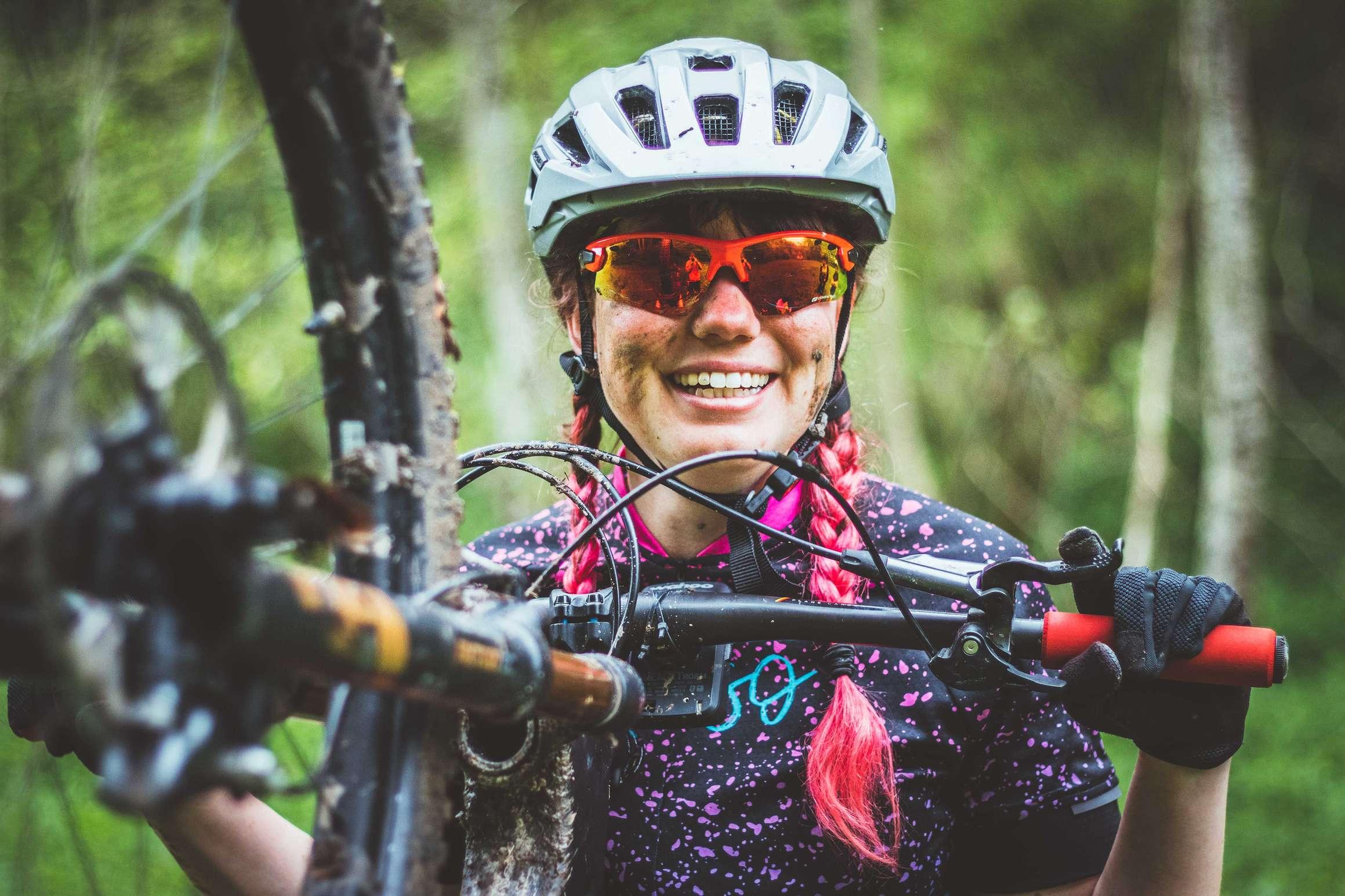 Glückliche Mountainbikerin lächelt in die Kamera