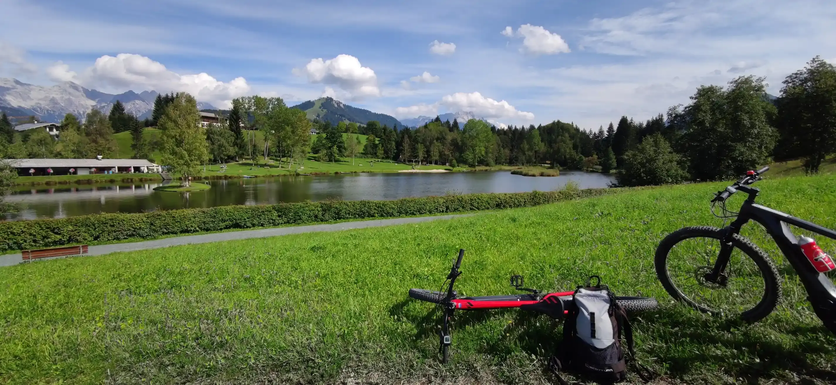 Zwei Fahrräder liegen auf einer Wiese, im Hintergrund ein See.