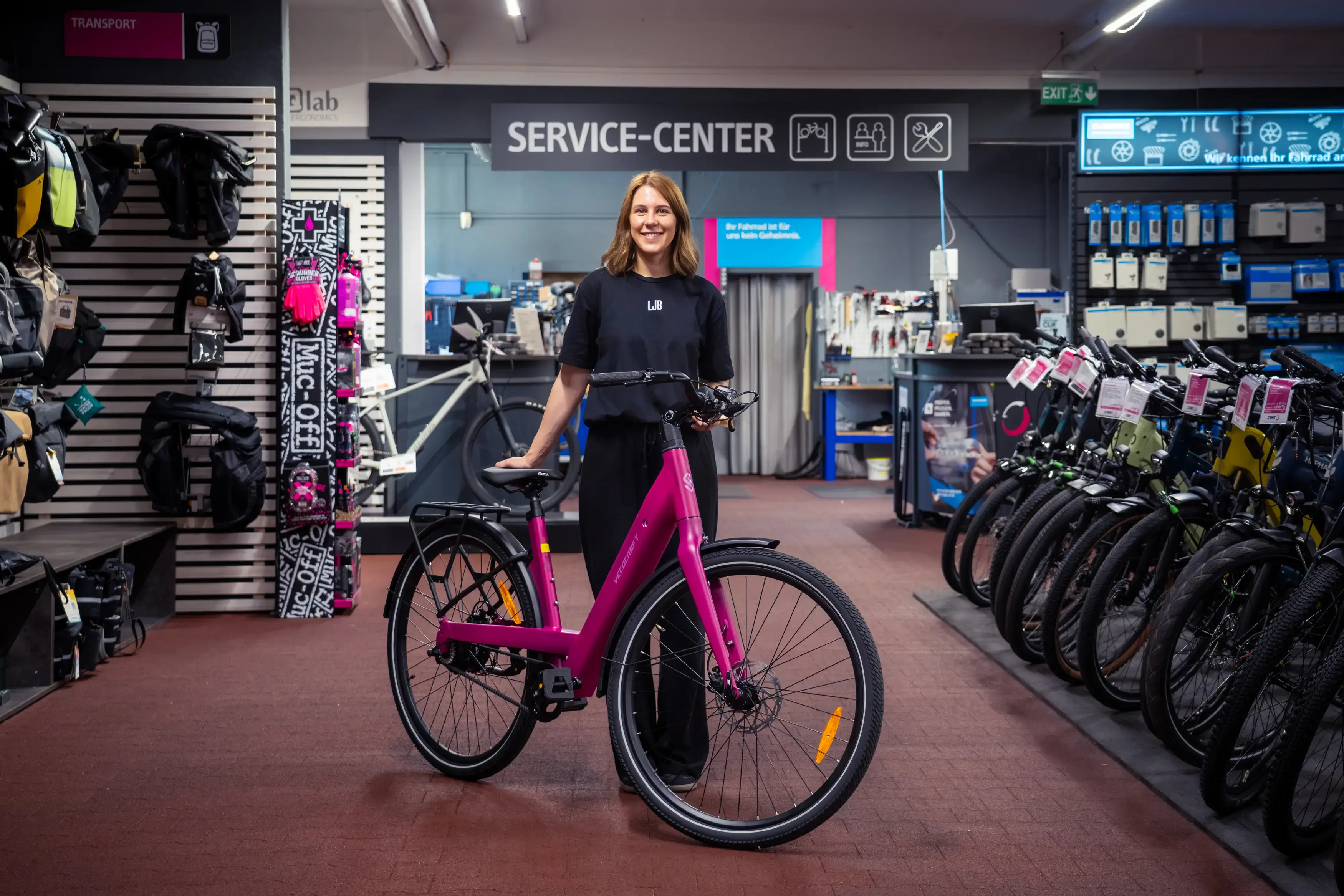 Mitarbeiterin von Little John Bikes mit einem pinken Leihrad in einer Filiale.