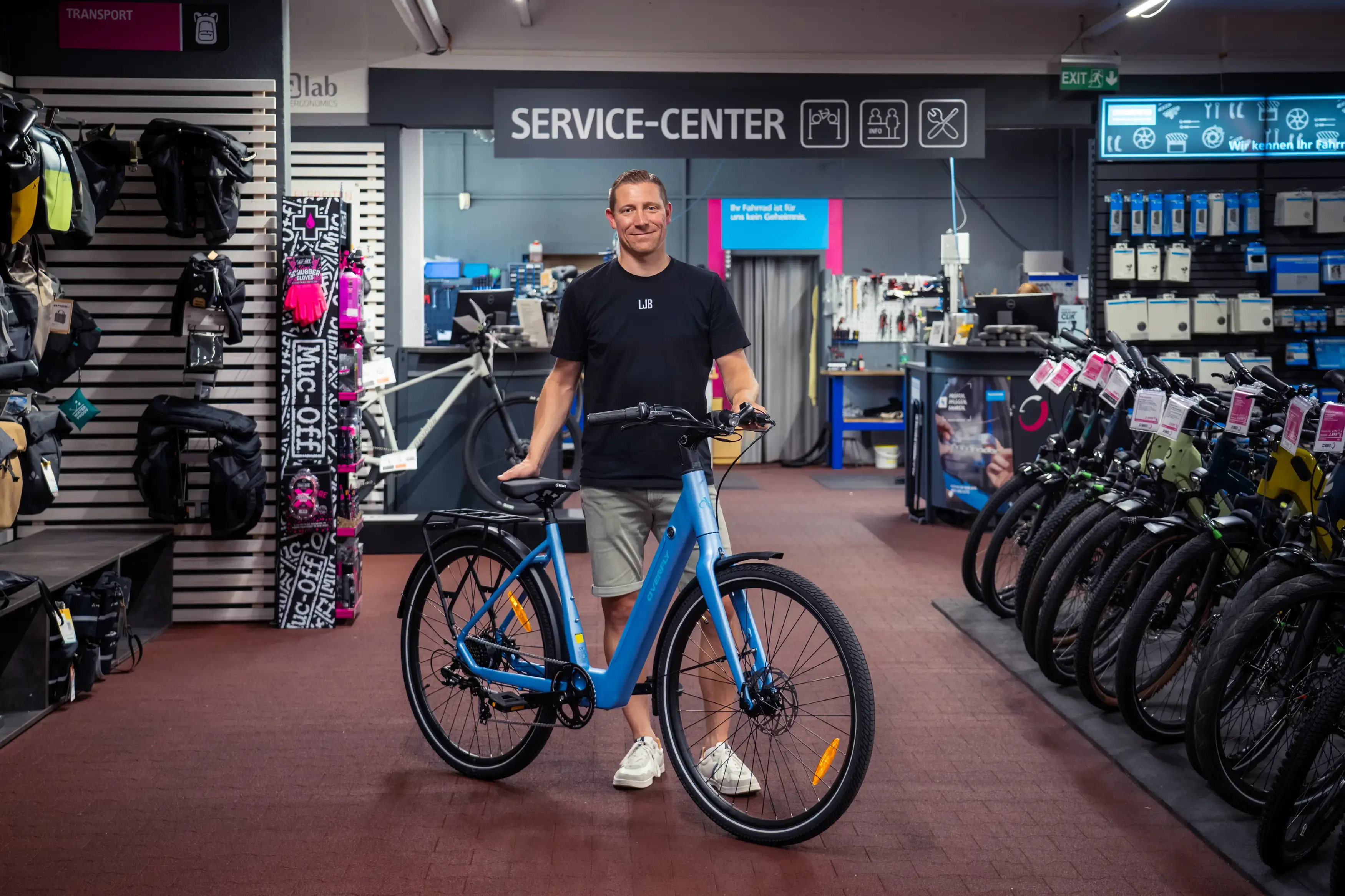 Mitarbeiter von Little John Bikes mit einem blauen Leihrad in einer Filiale.