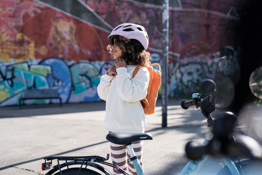 Kind mit Helm und Fahrrad steht vor einer bunten Graffiti-Wand.