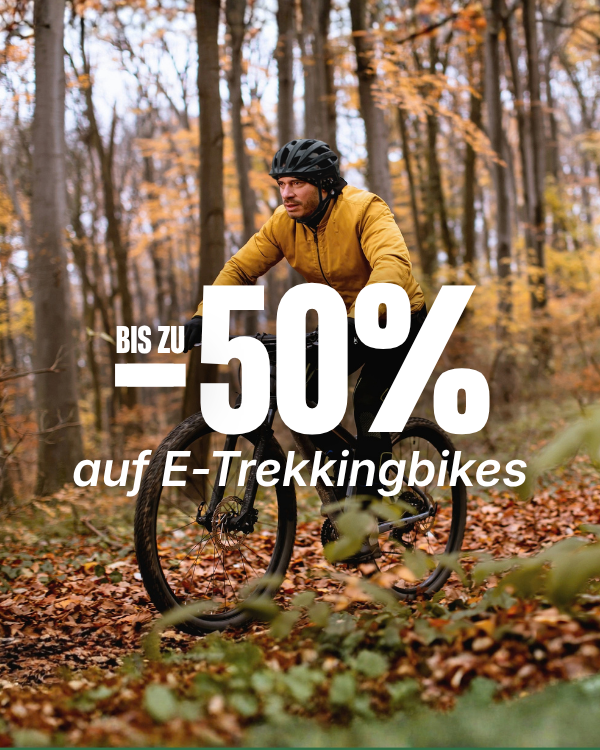 Mann auf einem E-Trekkingbike im herbstlichen Wald mit der Rabattaktion „Bis zu 50 % auf E-Trekkingbikes“.