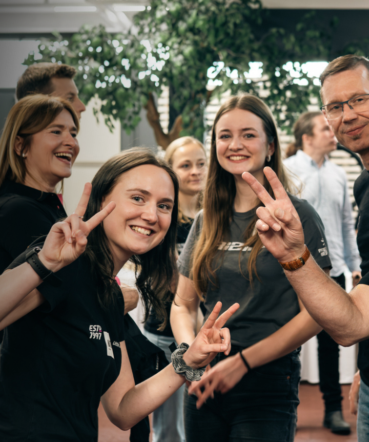Lachende Kollegen bei einer ljB Veranstaltung, zwei Personen zeigen das Peace-Zeichen.