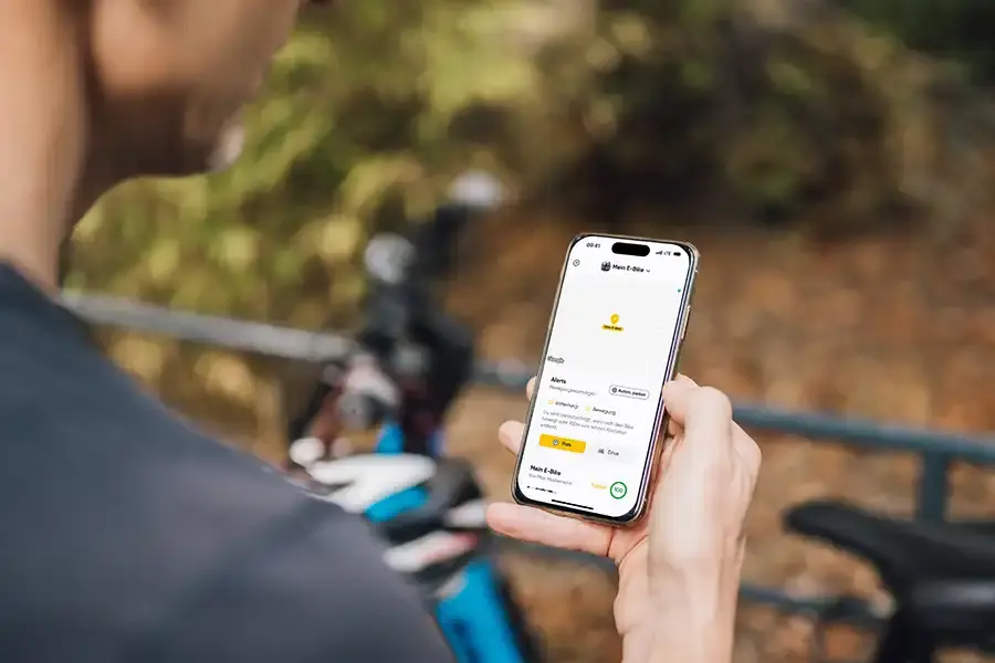 Person hält im Freien ein Smartphone mit dem Bildschirm einer Fahrradverleih-App