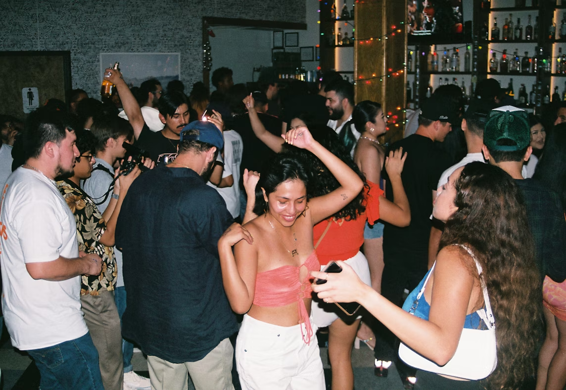 Nightlife party: Young crowd dancing at a busy club. Energetic group enjoying music on the dance floor.