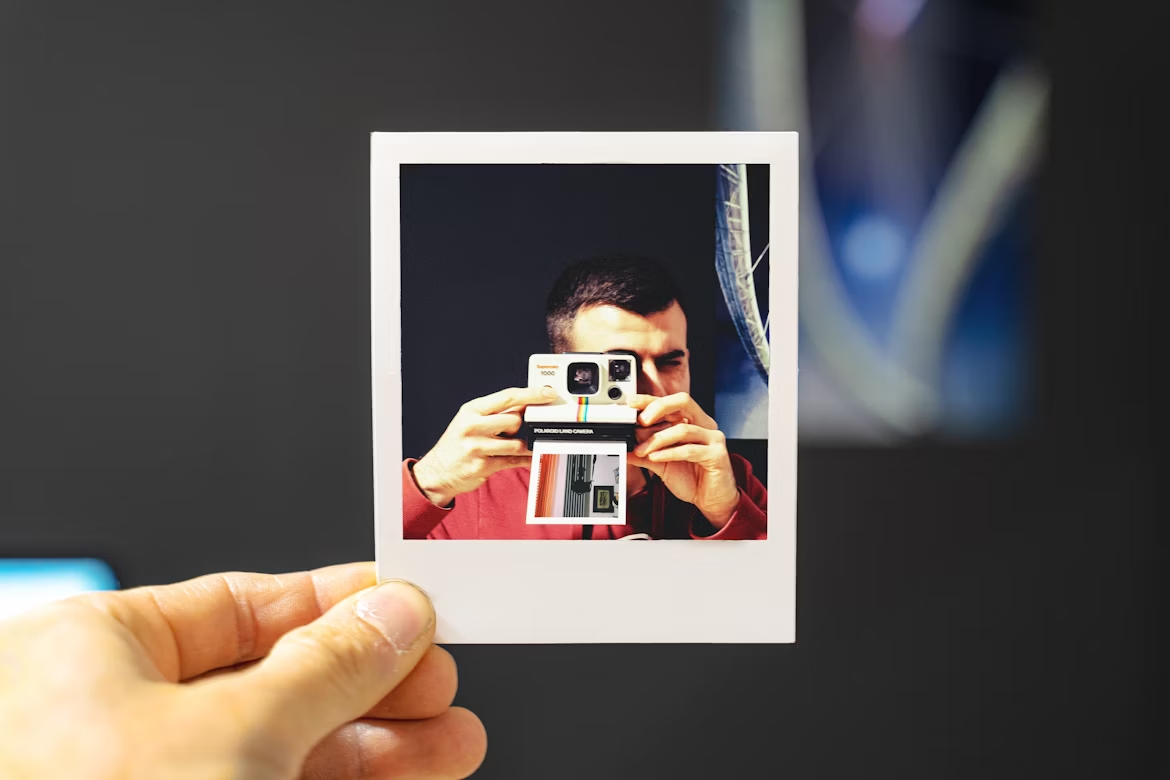 Polaroid-style photo of a person making a picture of themselves.