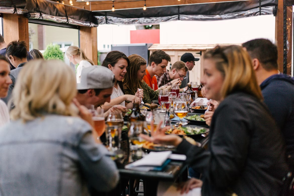 Corporate team lunch: Colleagues dining & chatting at outdoor party. Casual social gathering with food and drinks.
