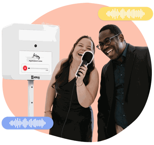 Two happy people holding a microphone in front of a KRUU photo booth, using the audio feature.