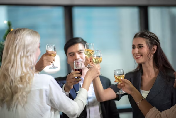 Corporate celebration: Happy business team toasting with wine. Colleagues celebrating success at office party.