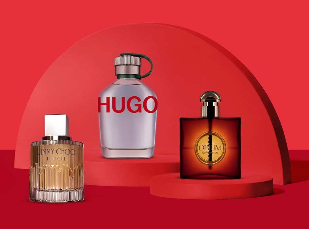 Three perfume bottles on red podiums: Jimmy Choo Illicit, Hugo, and Opium, set against a red geometric background.