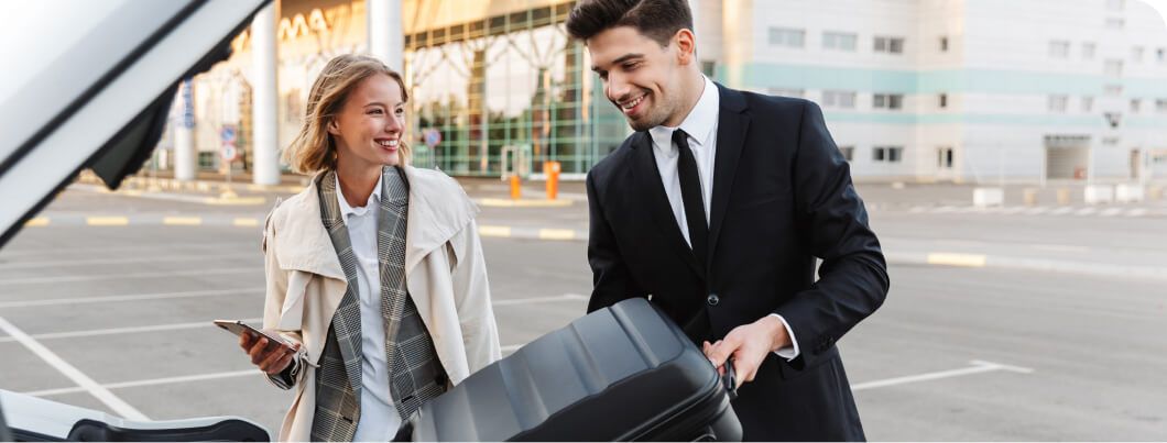 an assistant placing a suitcase in a car